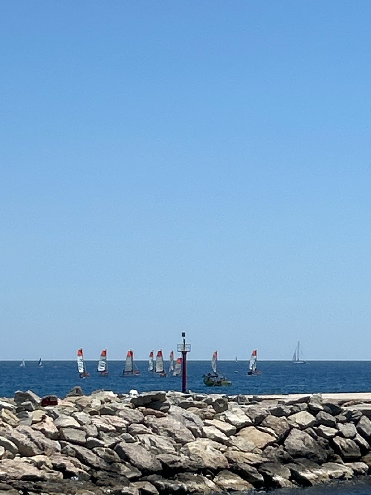 Barcelona waterfront: calm sea, sailboat, skyline on a clear morning