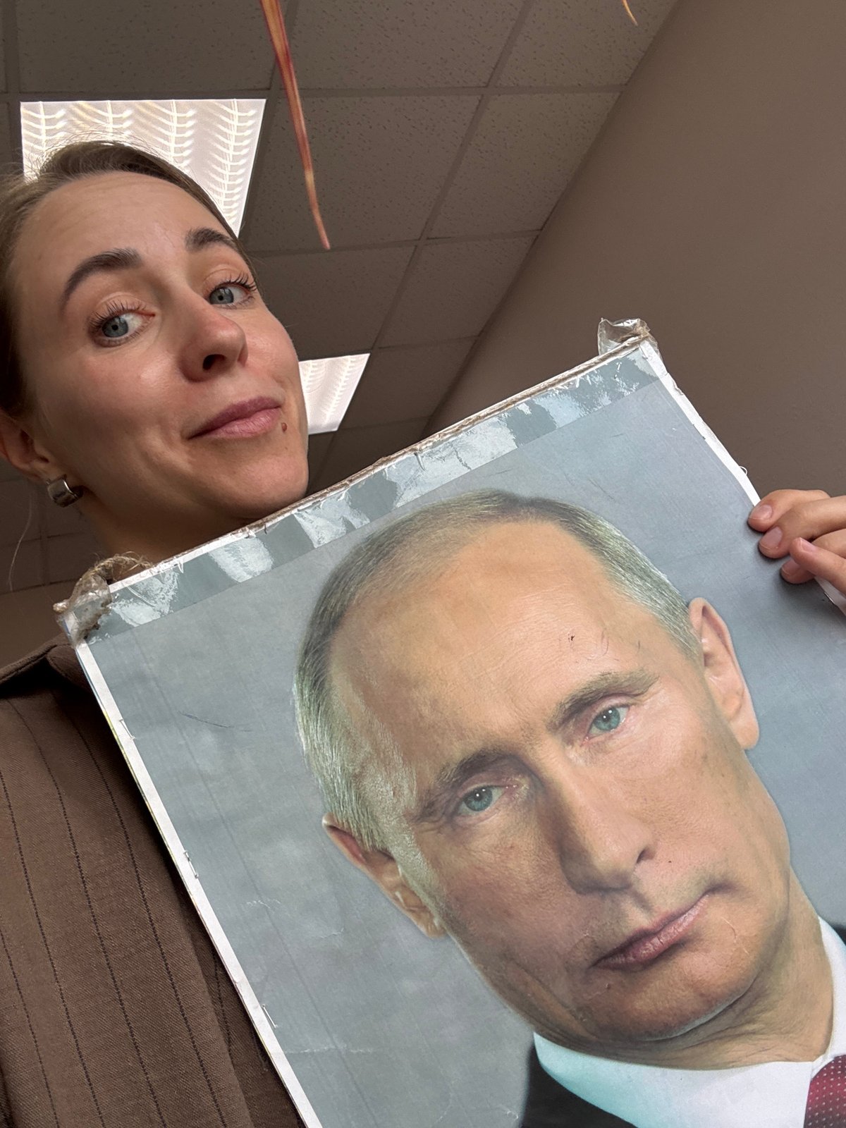Woman holds damaged Putin portrait in Russian city
