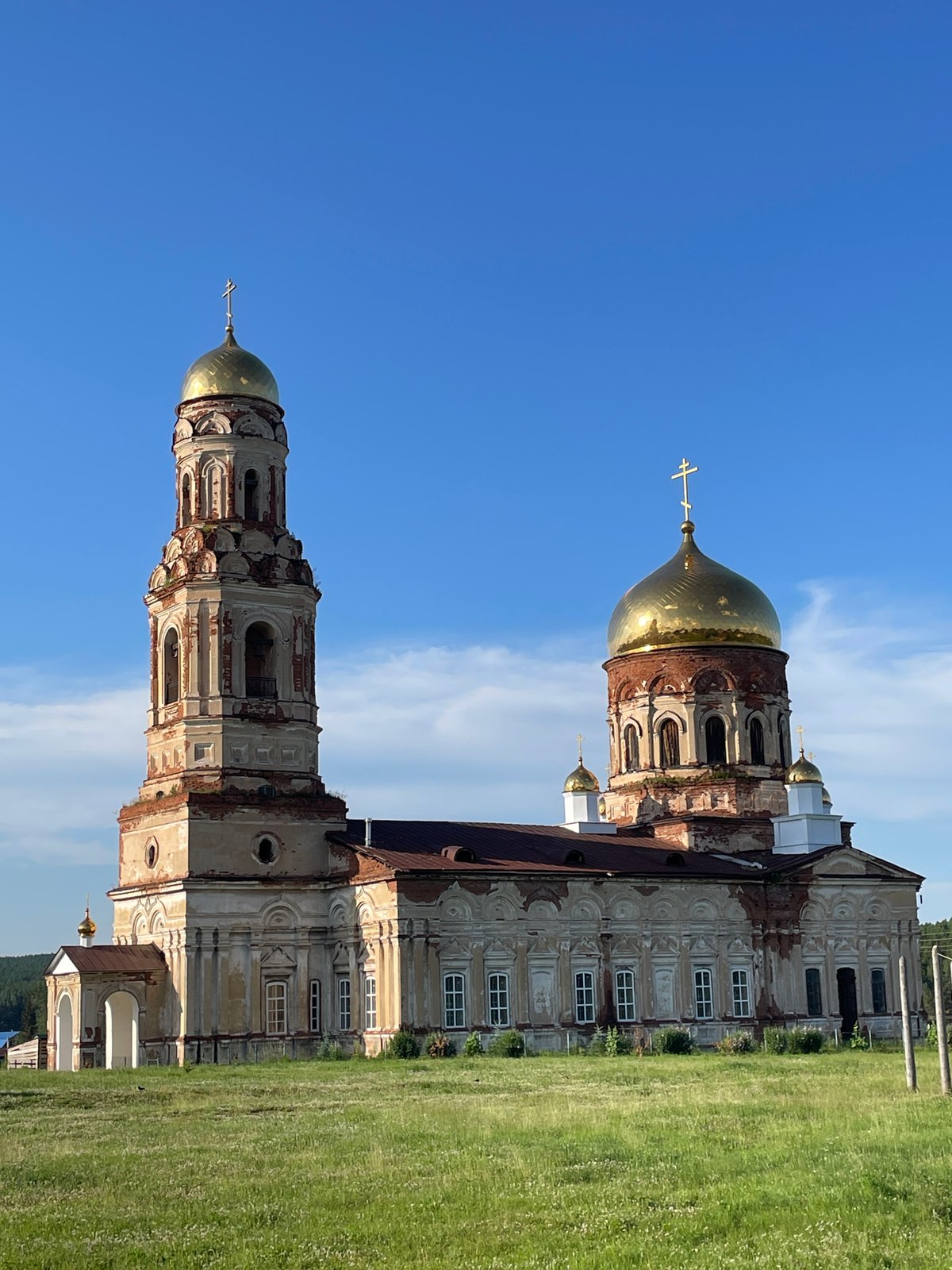 Weathered Orthodox church with golden domes in rural Russia