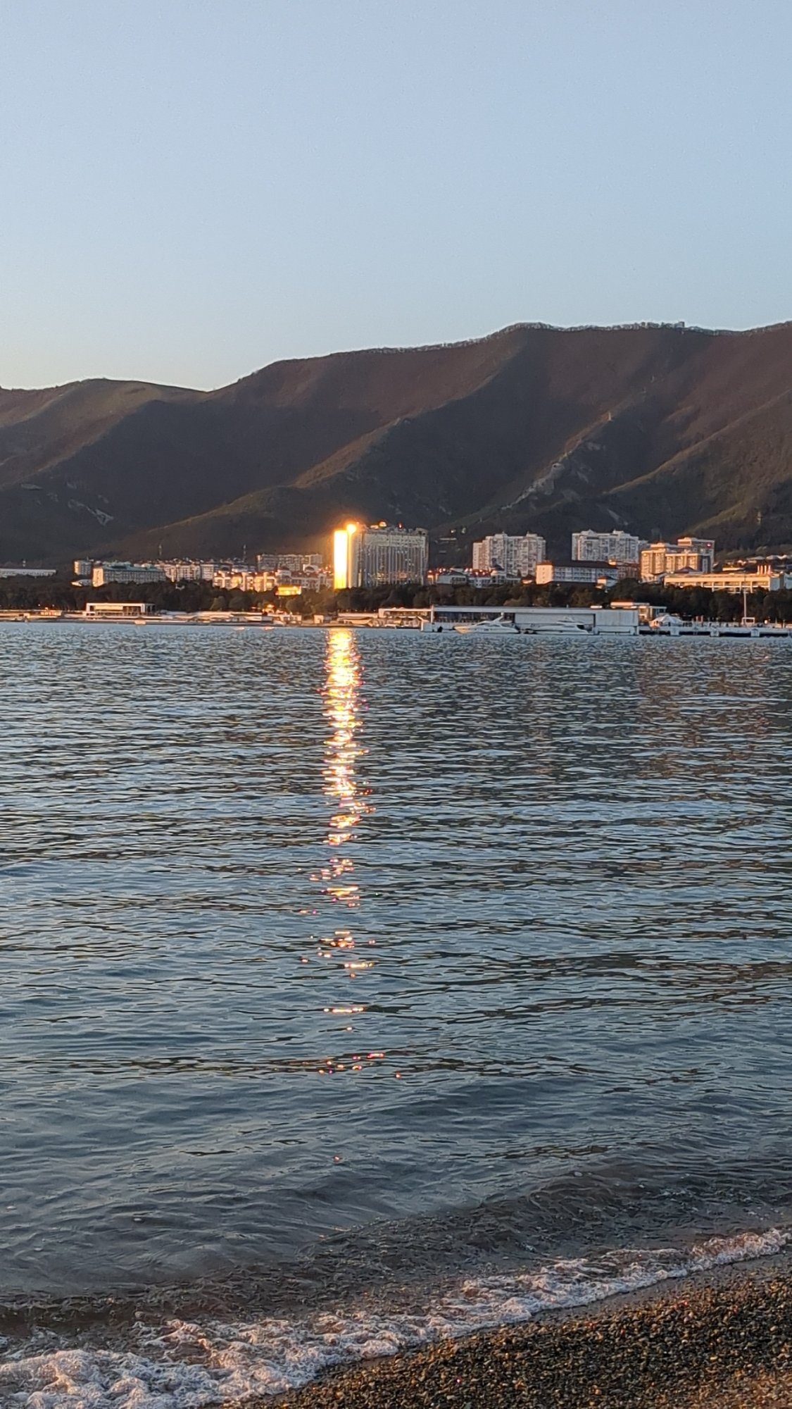 Witness documents peaceful sunset over water from rocky shore