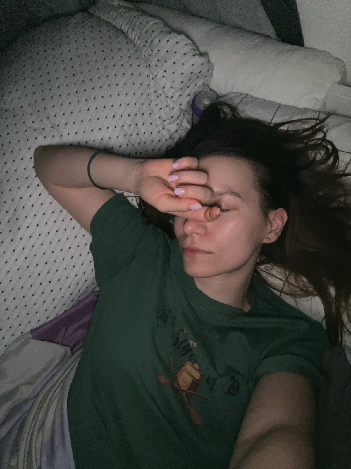 Woman rests in bed wearing Slytherin shirt in Limassol