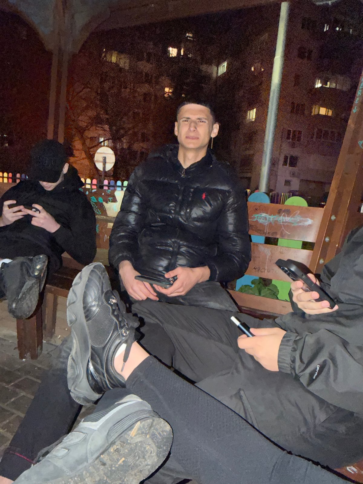 Three people gather outdoors in urban nighttime setting