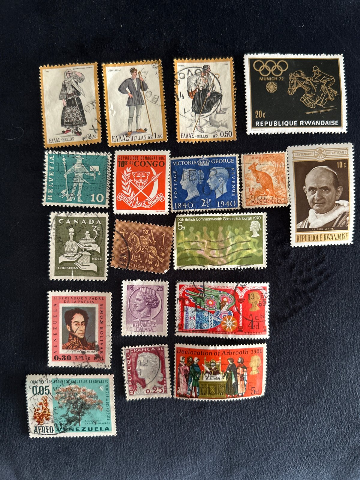 Vintage stamp collection spread across dark fabric, multiple countries