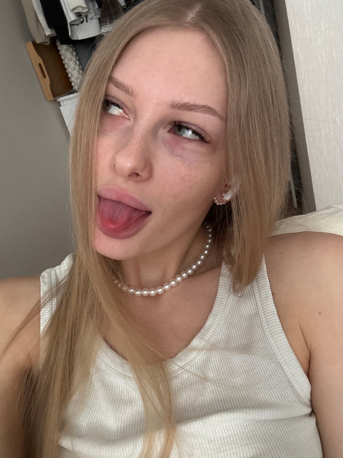 Woman photographed in white top, pearls in Perm apartment
