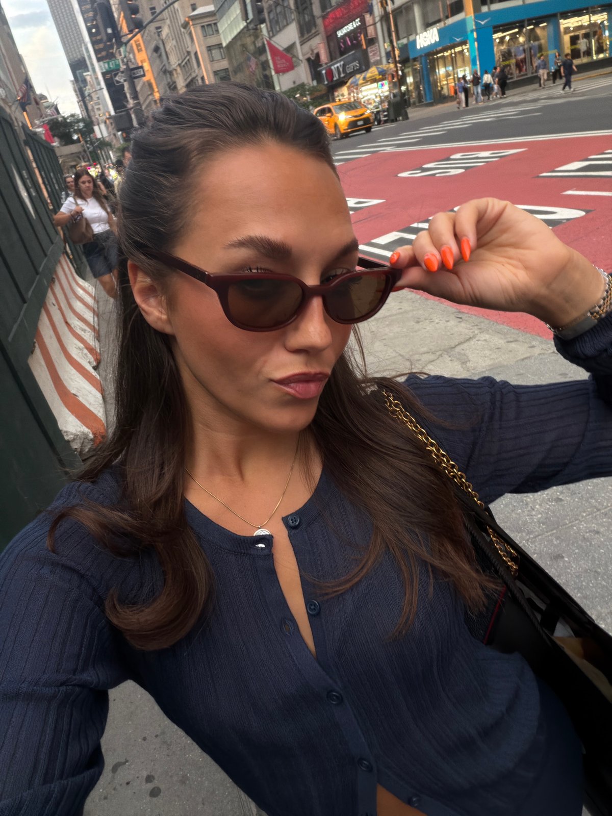 Woman adjusts sunglasses during dramatic New York sunset