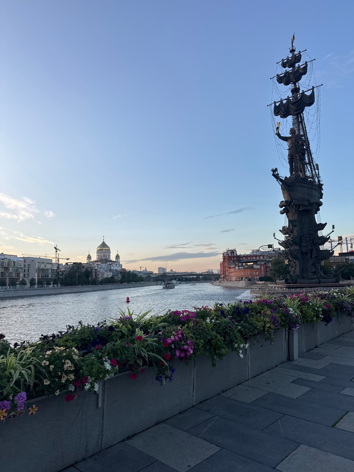 Dusk along the Moskva River, landmarks and a dog mid-walk.