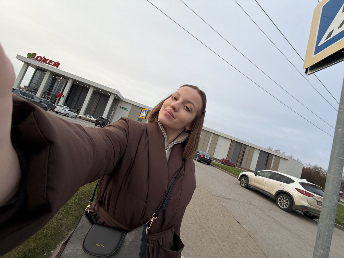 Woman takes selfie outside OK'EJ building in Klin, Russia