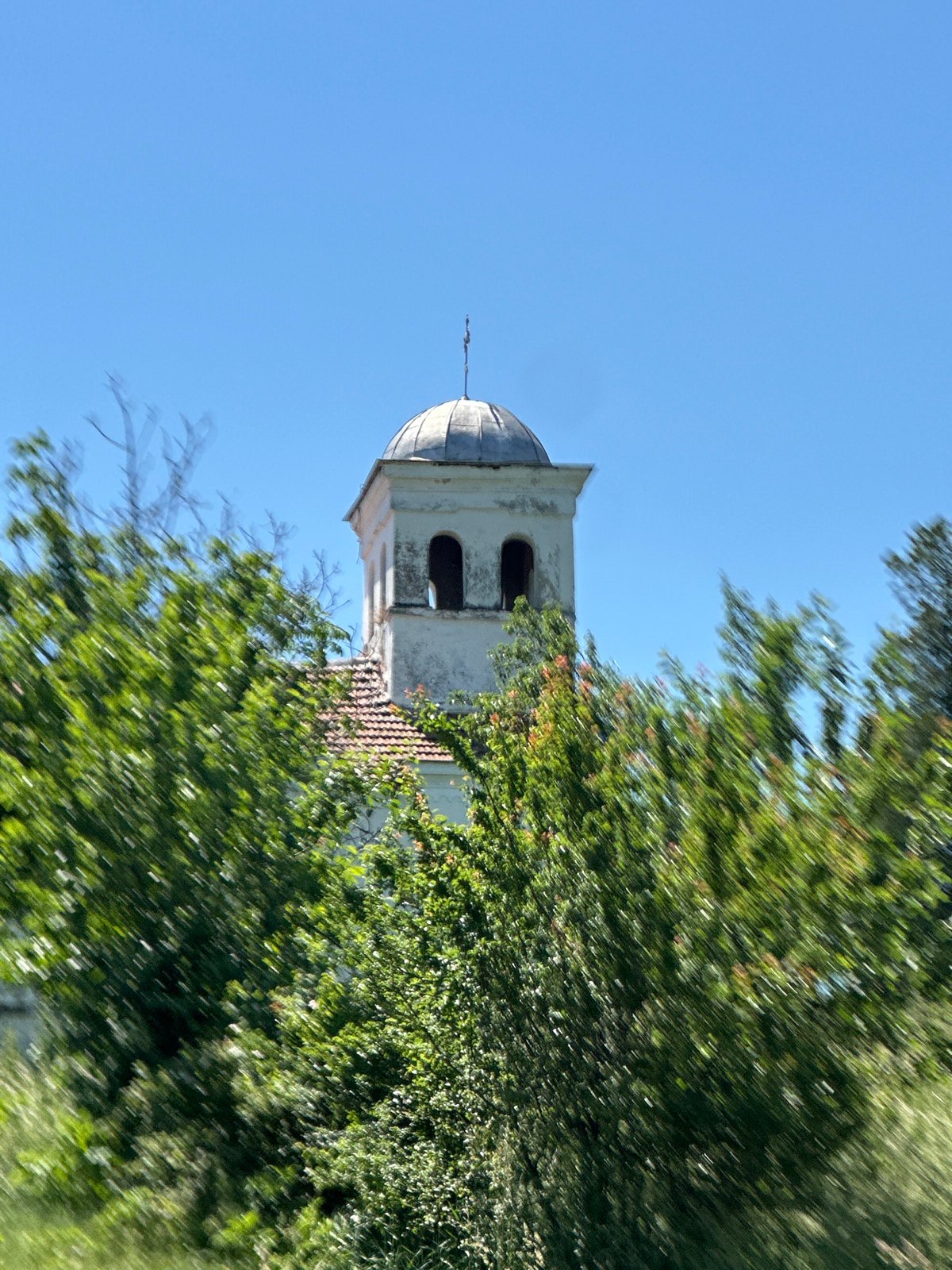 Church tower photographed through foliage in Slavyani, Bulgaria