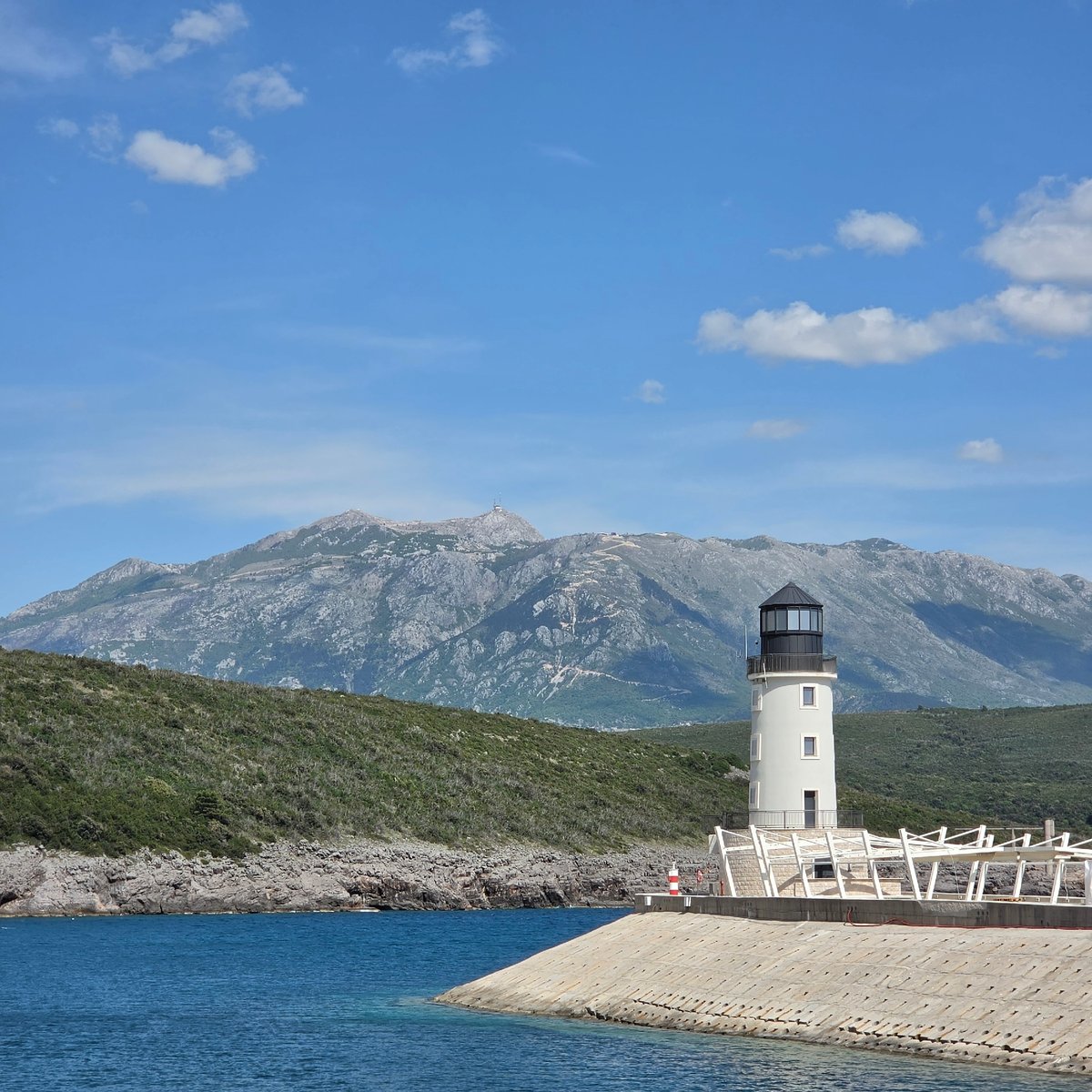 White lighthouse observed against mountains near Radovići, Montenegro