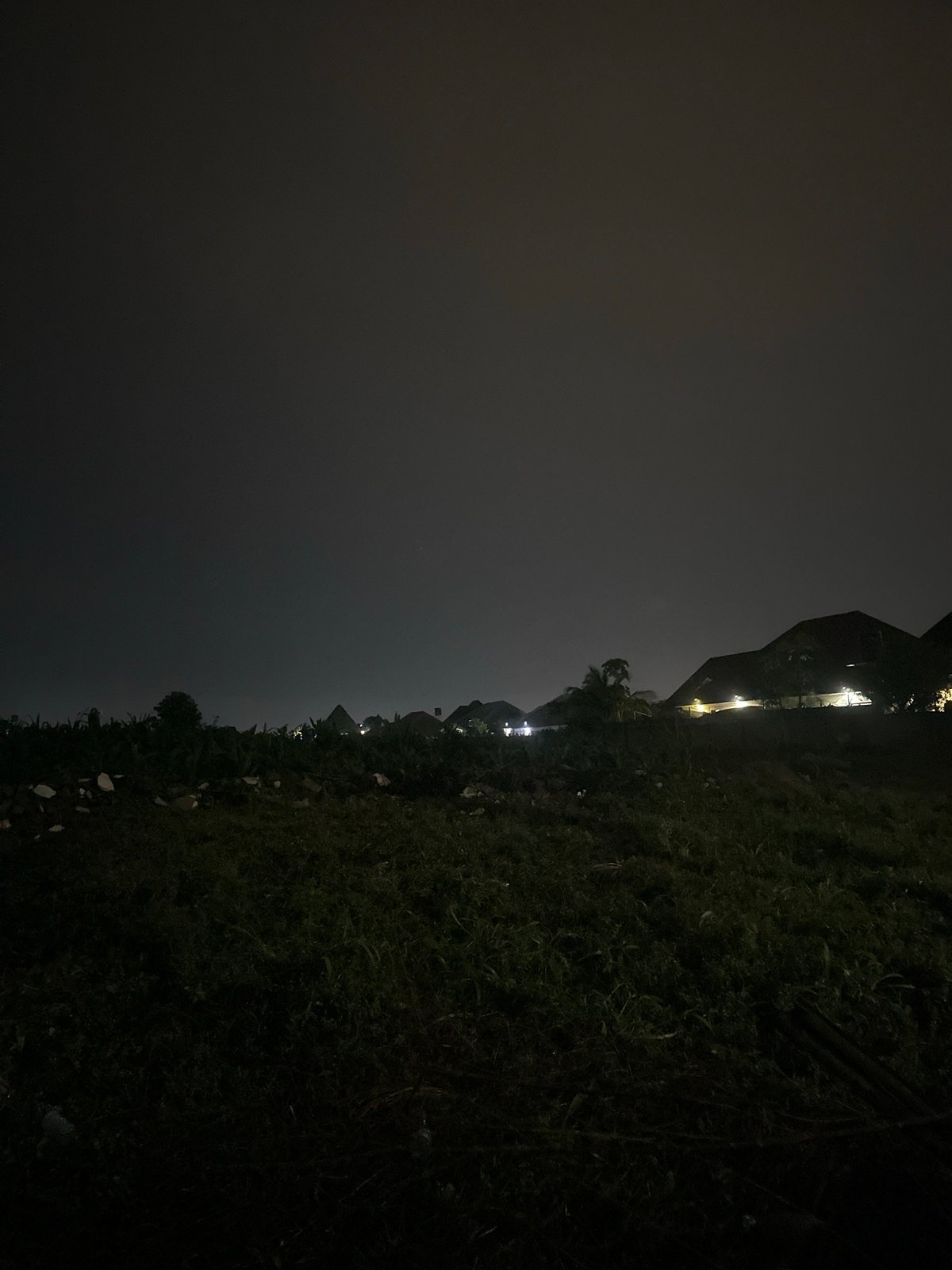 Wet Abuja streets and gated homes late on a rainy night