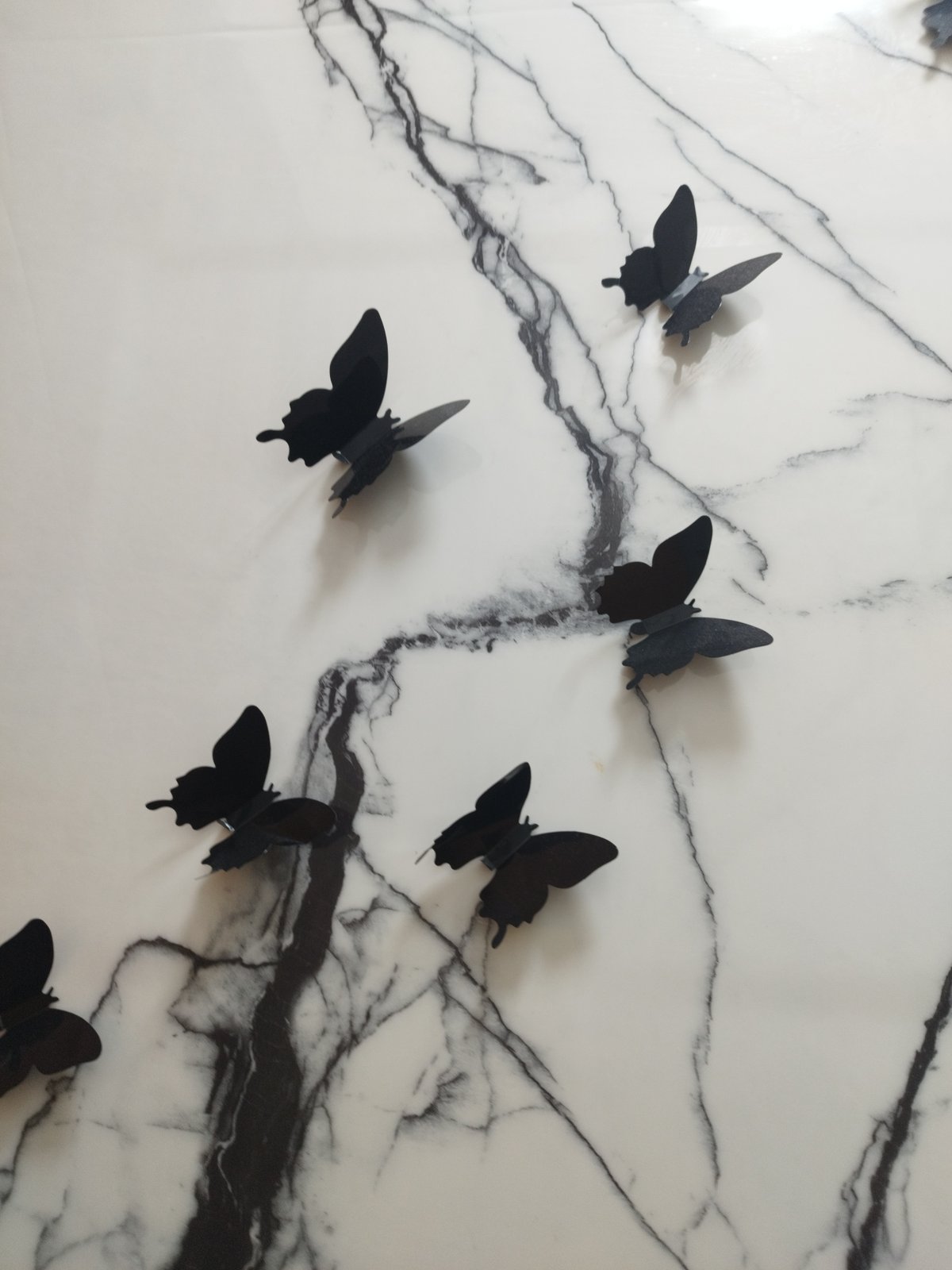 Black butterfly decals on marble-veined white surface in Astana