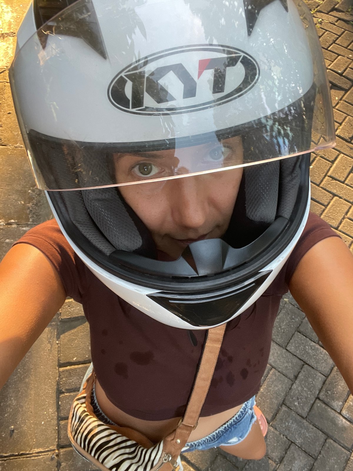 Person with motorcycle helmet spotted on sunlit city walkway