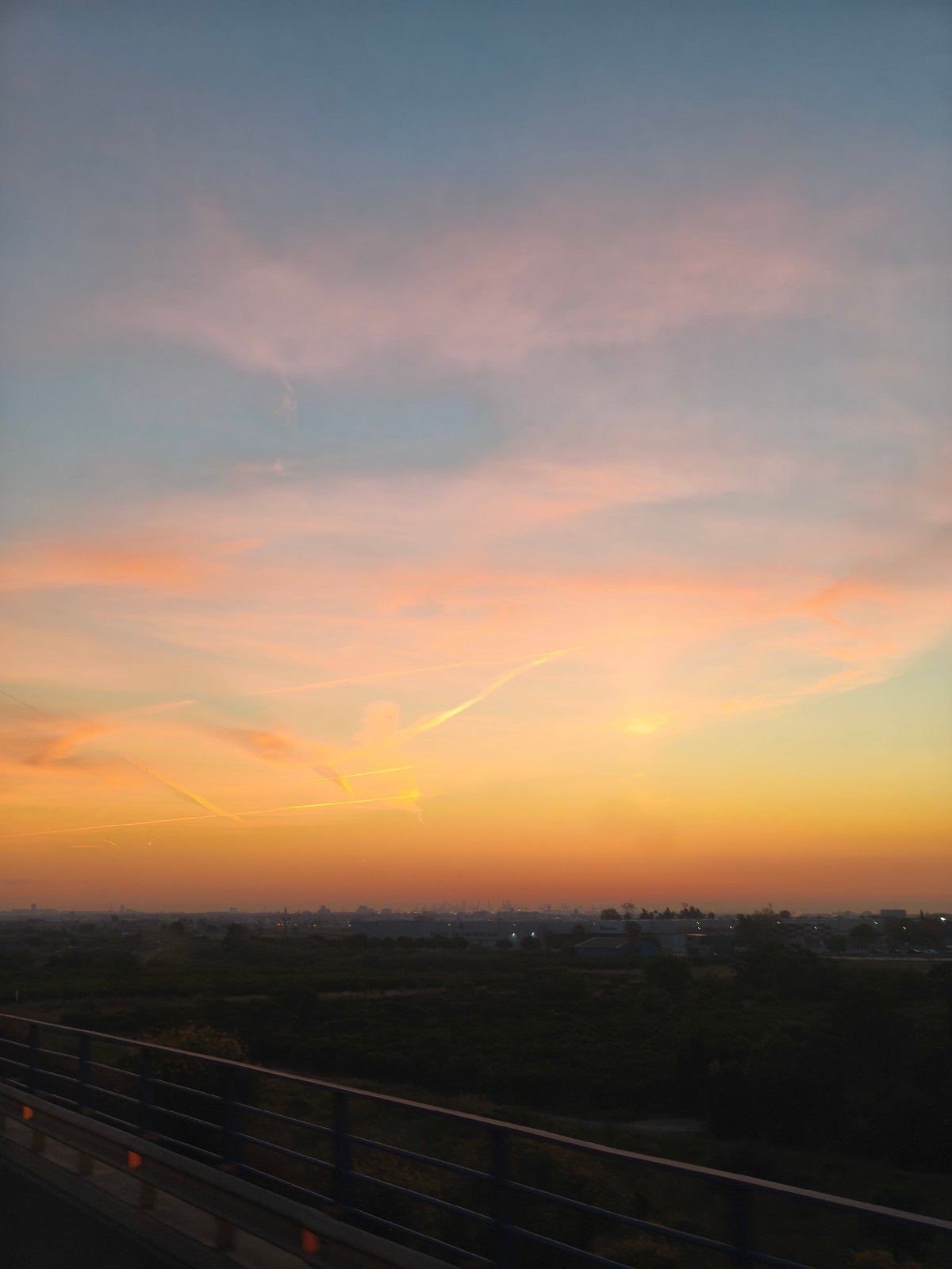 Sunset captured over Alcàsser, Spain with contrails and bridge