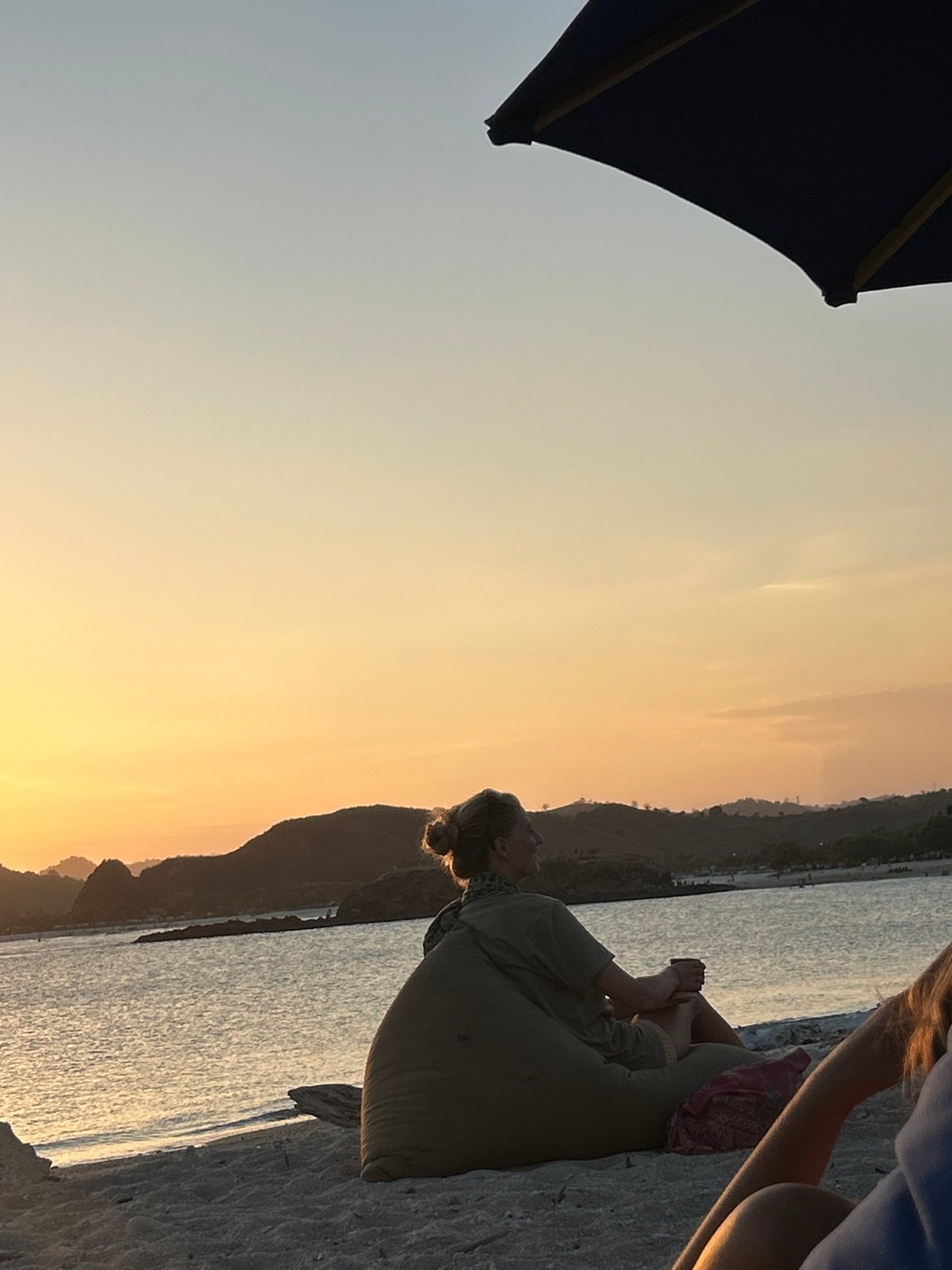 Kuta beach sunset, beanbag chairs, drinks, golden hour vibes.