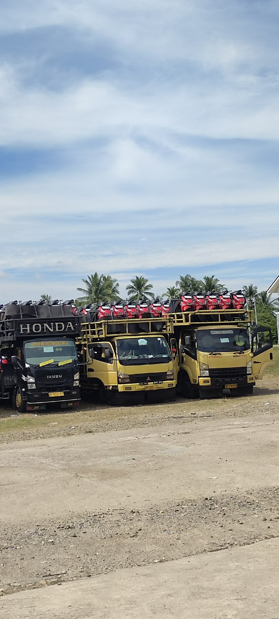 Honda scooter delivery trucks parked near a mosque in Aceh