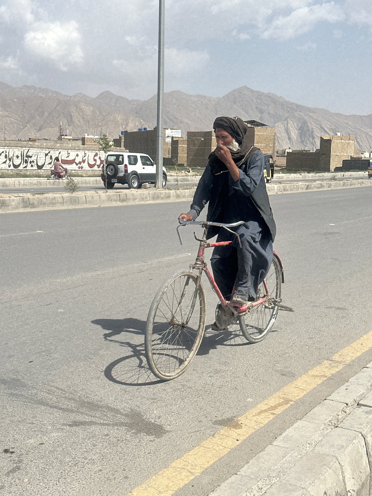 Cycling through Quetta in dark traditional dress