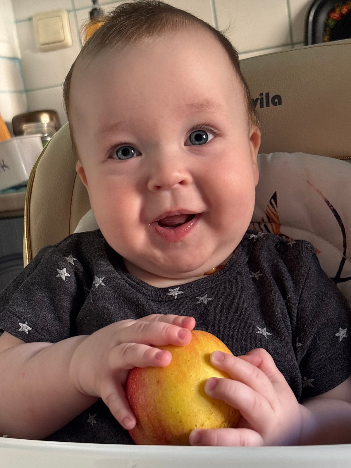 Baby holds apple during early morning feeding in Russia