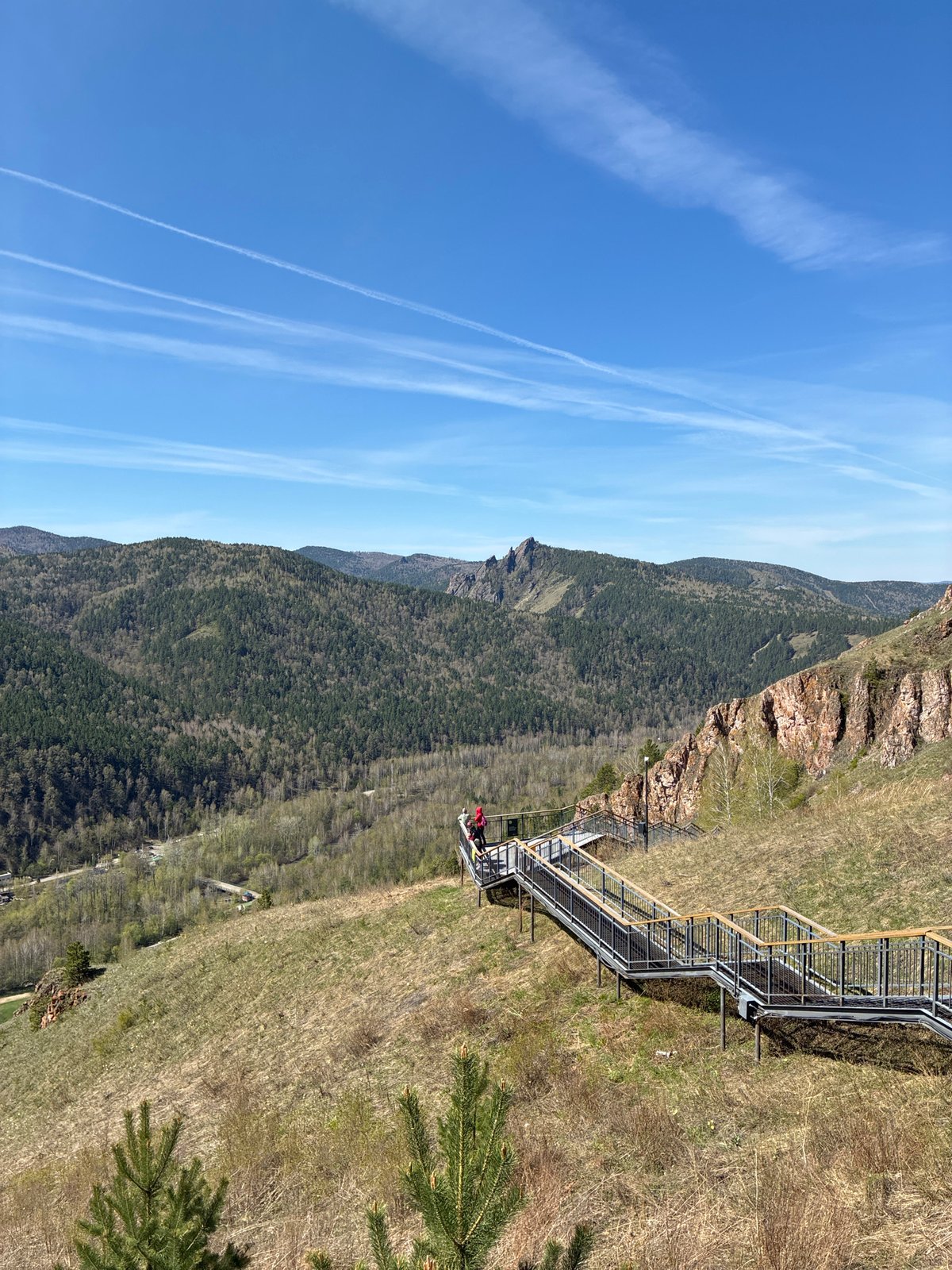 Mountain hikers climb metal stairs amid rocky terrain