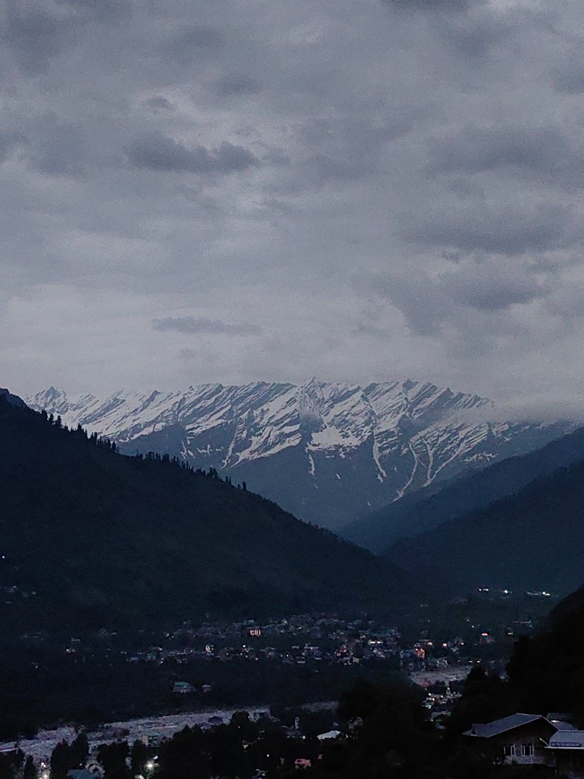 Vashisht village at dusk, Himalayas looming under heavy clouds