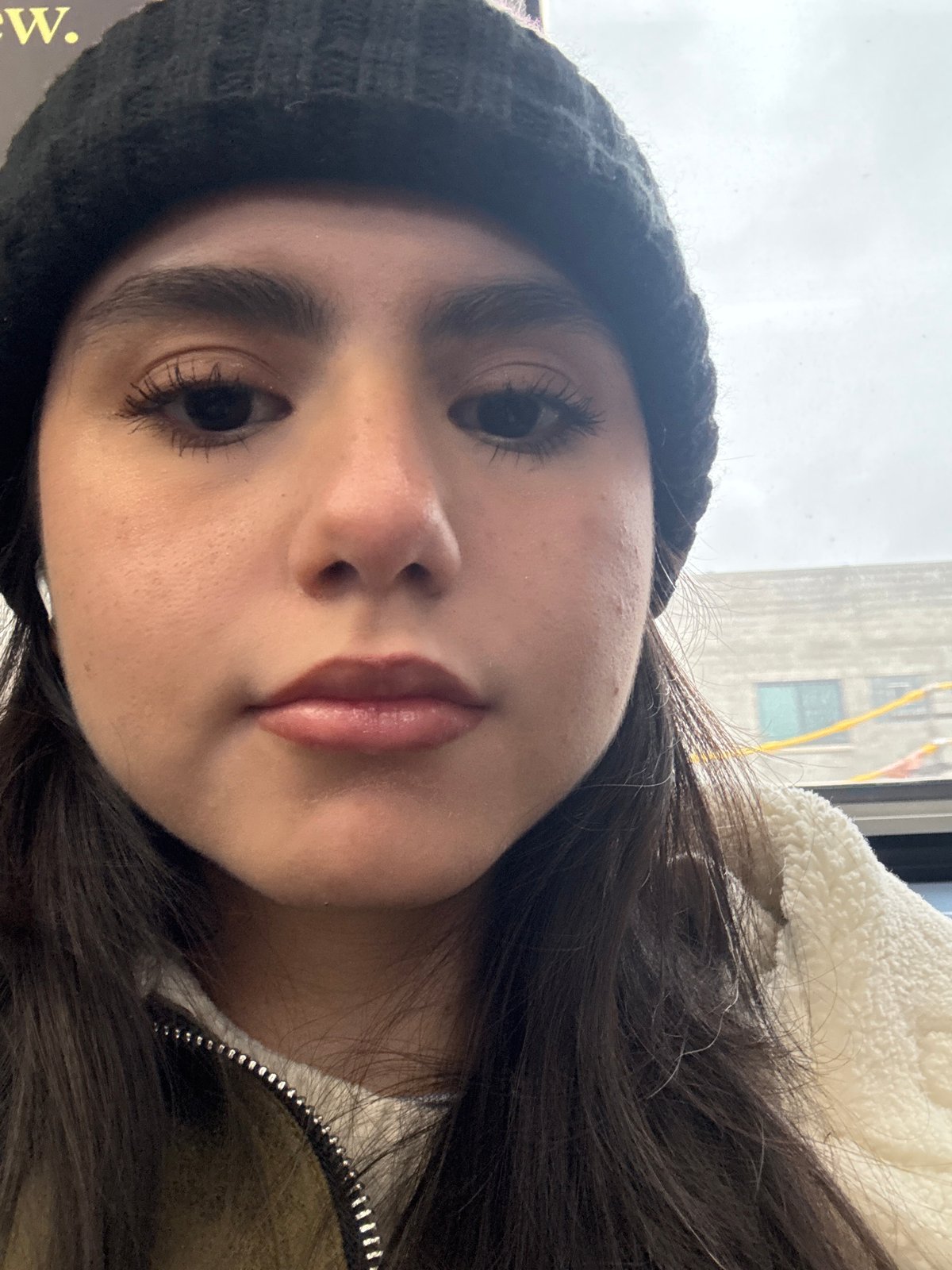 Woman takes selfie in Chicago wearing black cap, white jacket