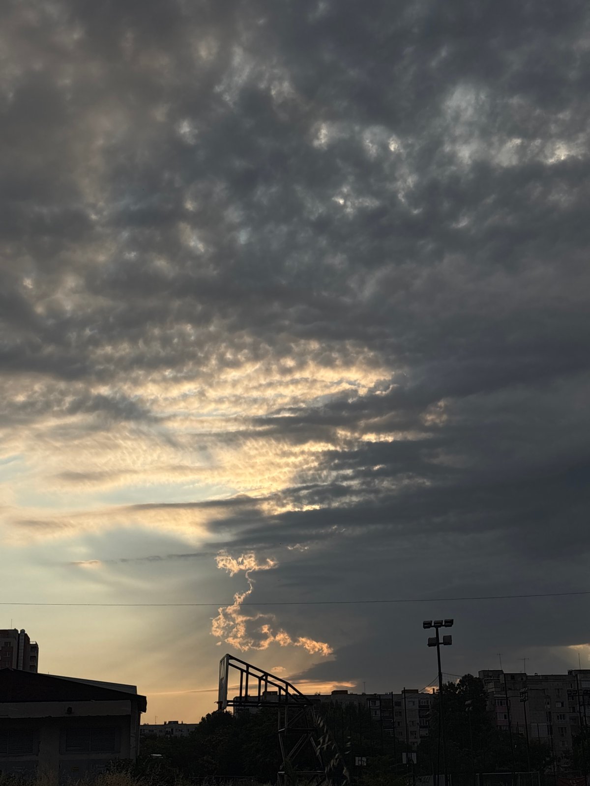 Golden light breaks through cloud cover over an urban skyline.