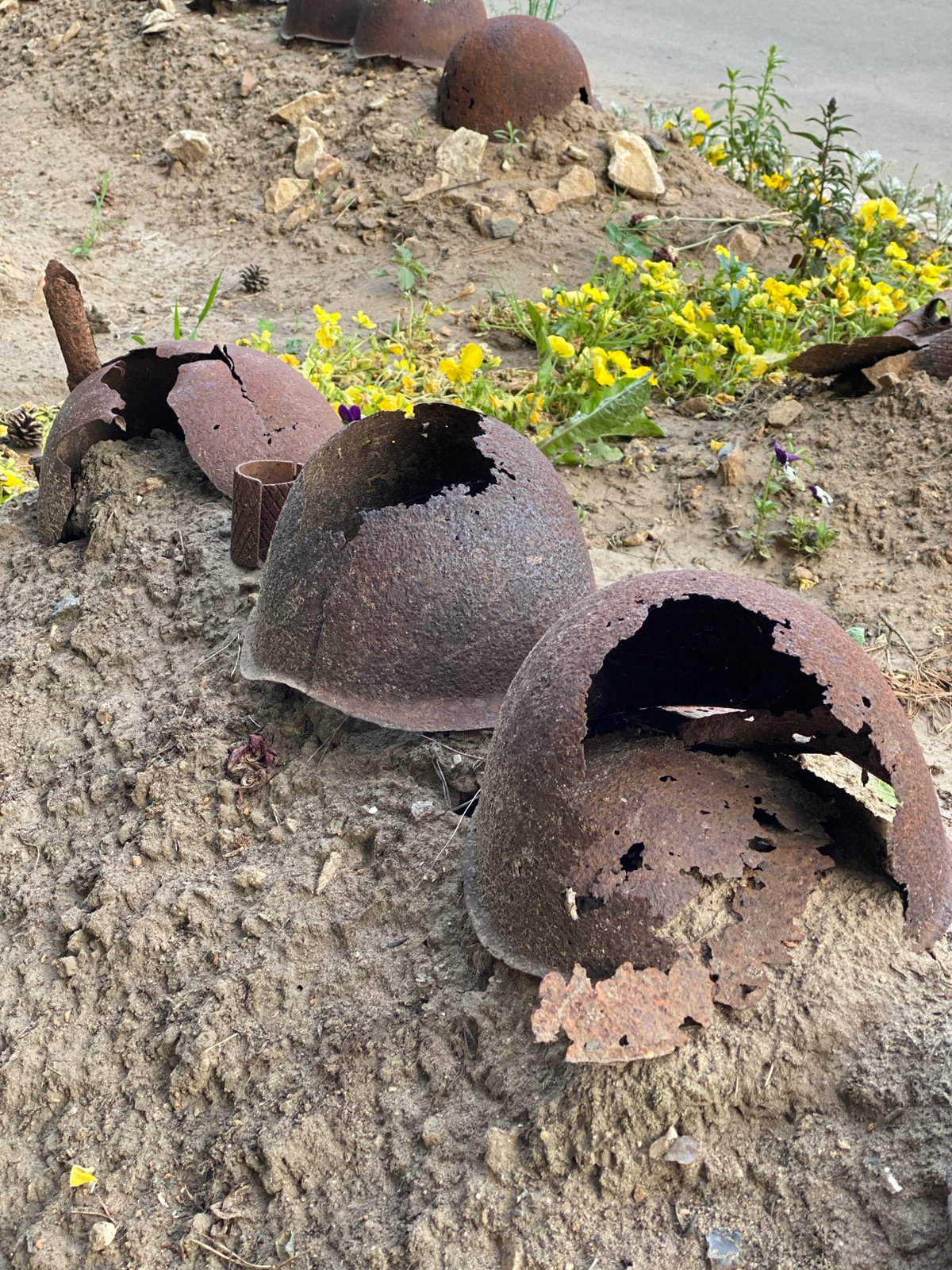 Rusted military helmets found on sandy ground in Russia