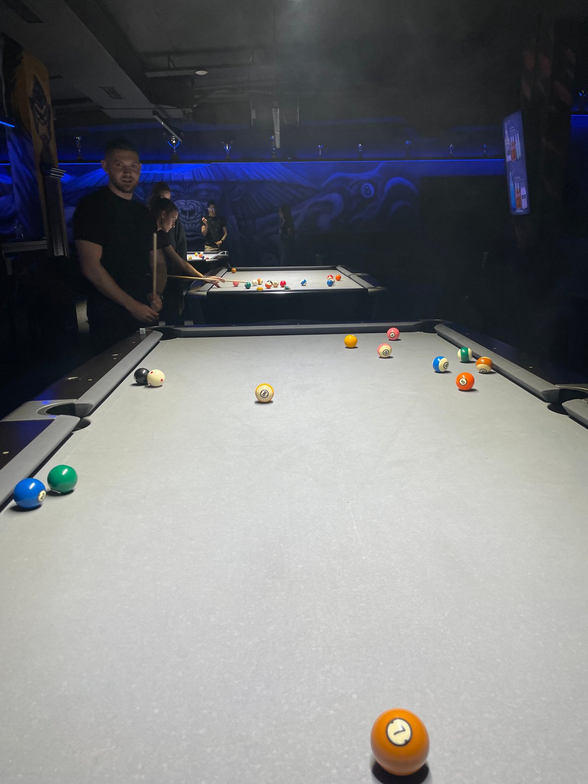 People gather in dimly lit billiard room