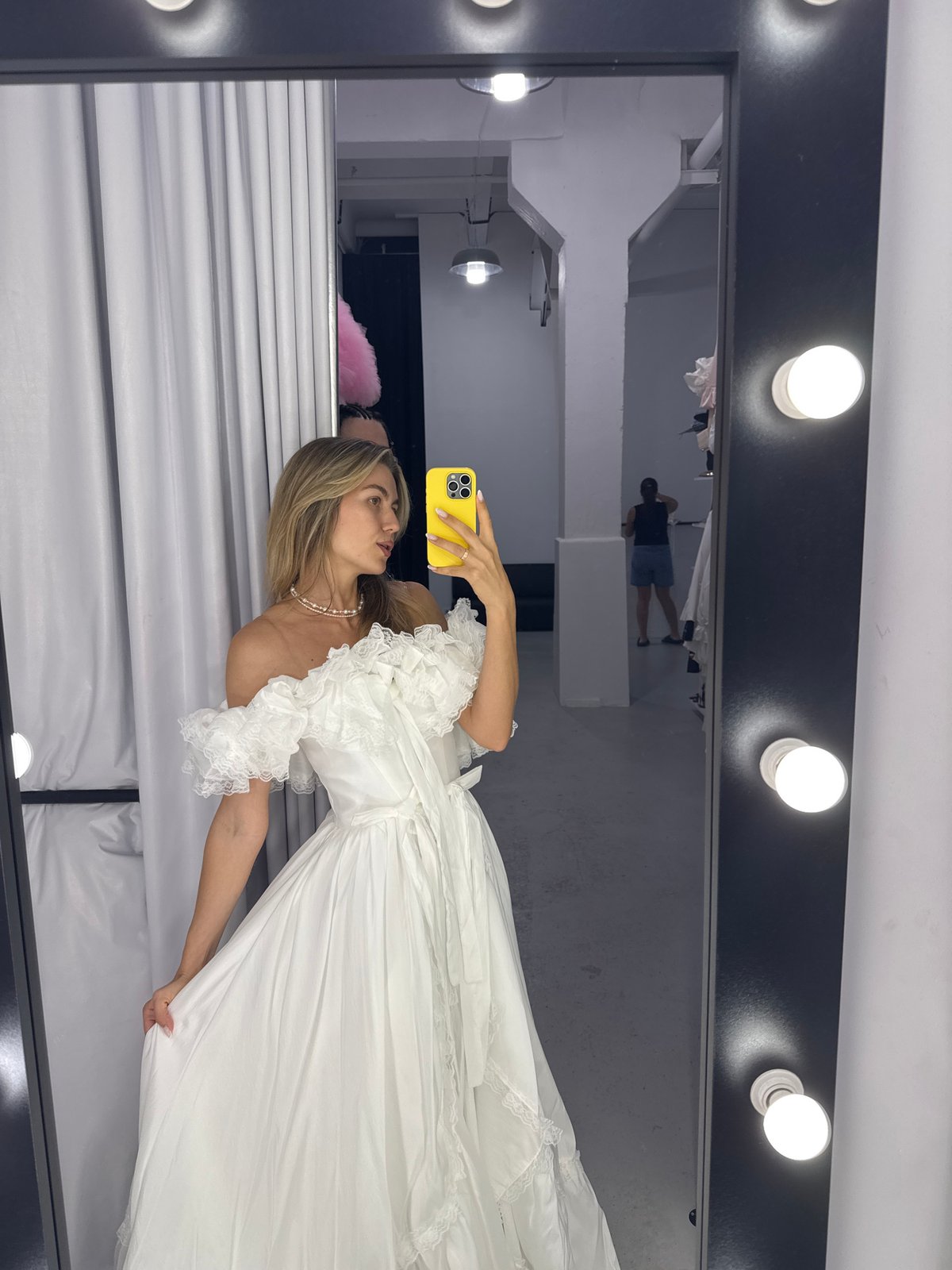 Woman in white dress takes selfies amid decorative interior spaces