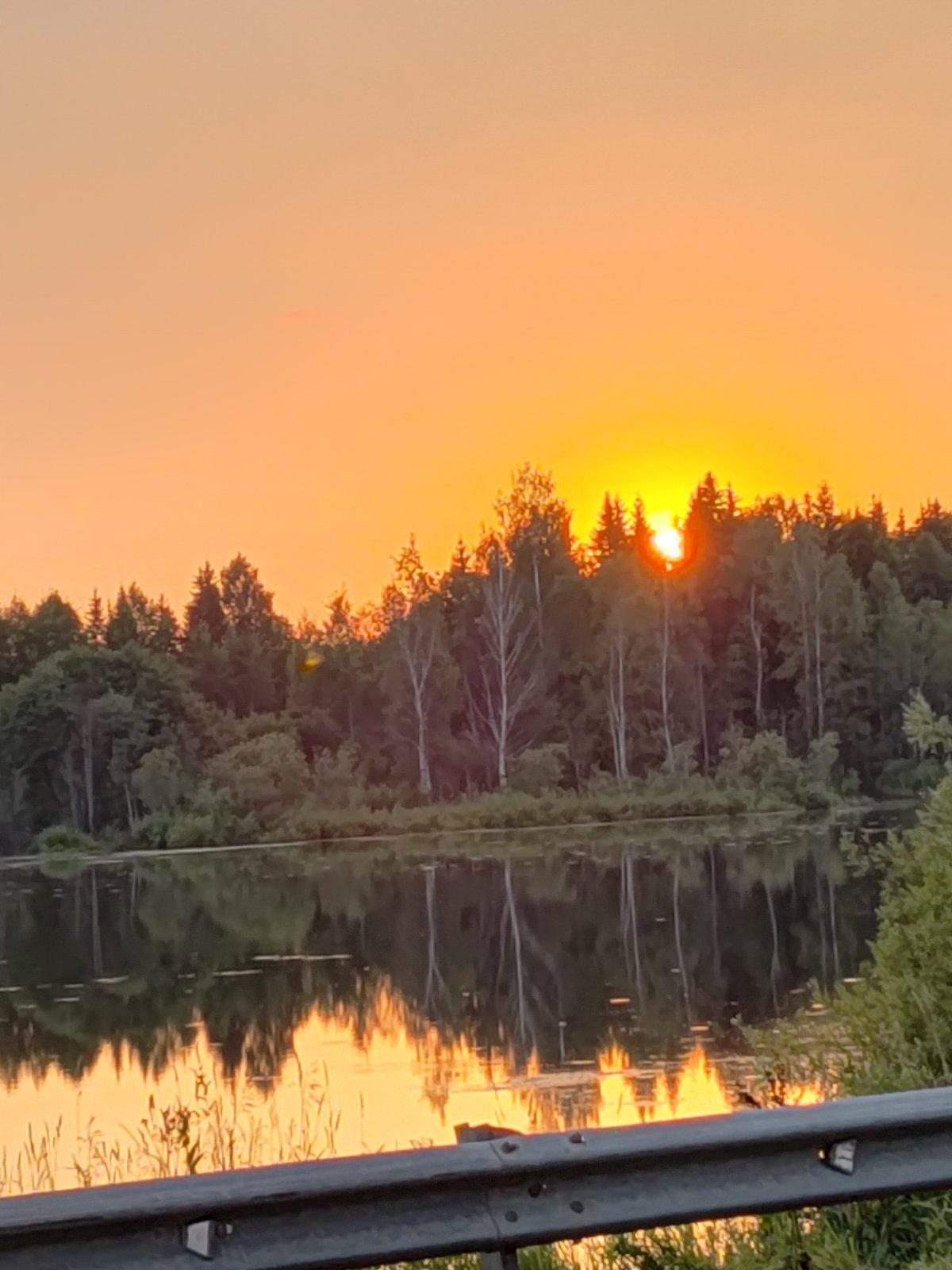 Sunset over a tree-lined waterway in Votkinsk, Russia