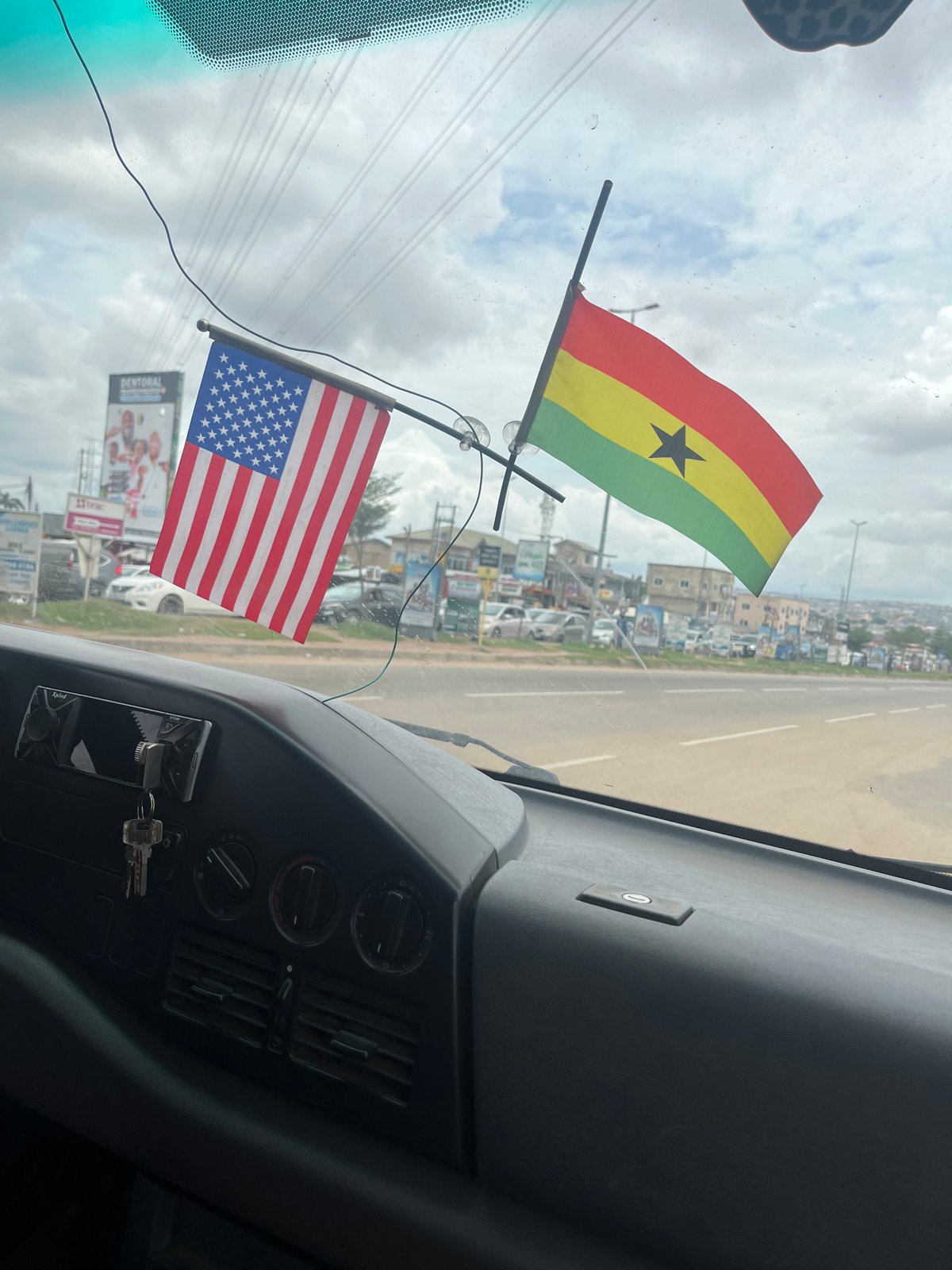 Vehicle interior captured with flags on windshield in Ablekuma