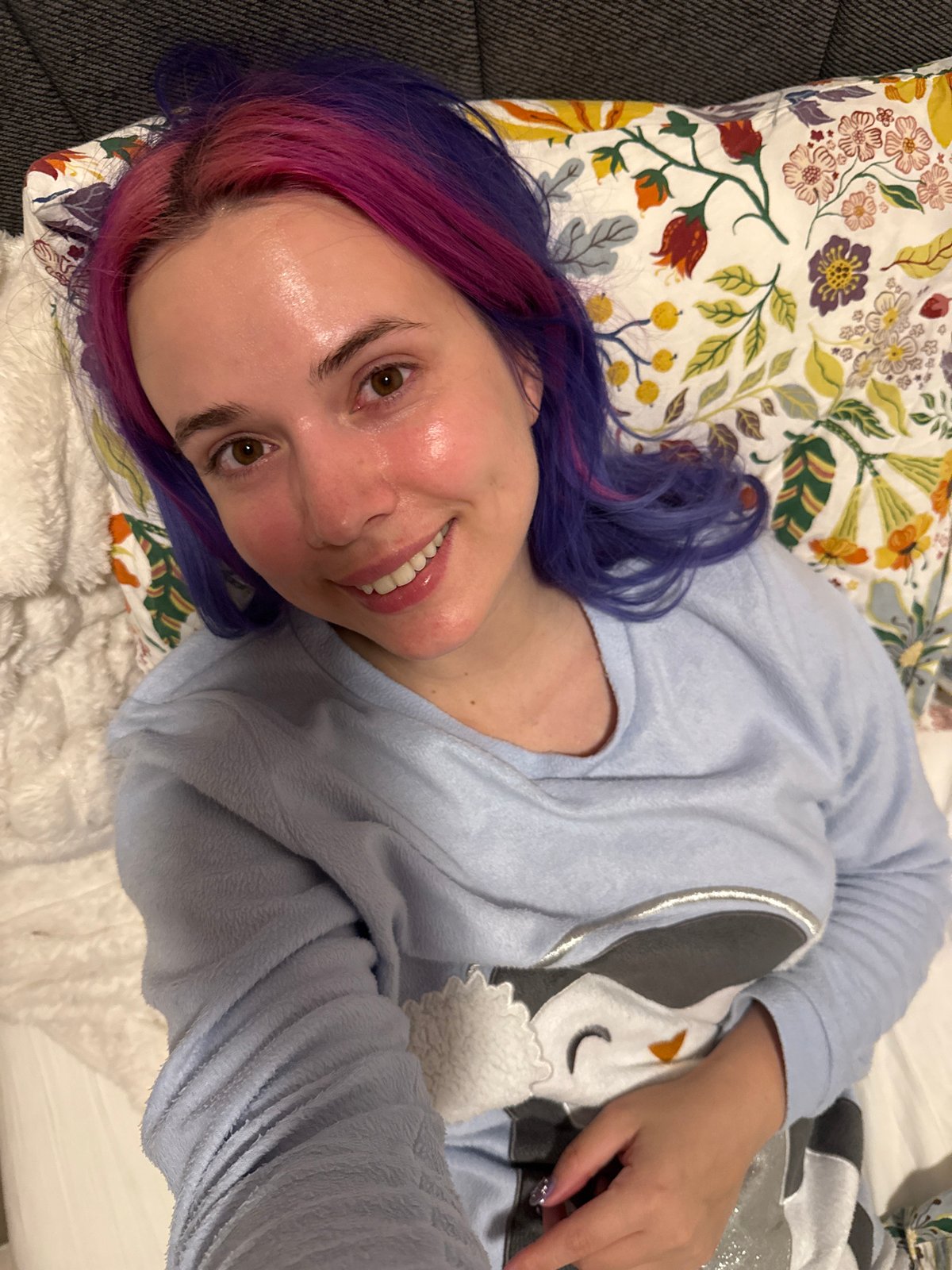 Woman with colorful hair rests in bed in Zagreb