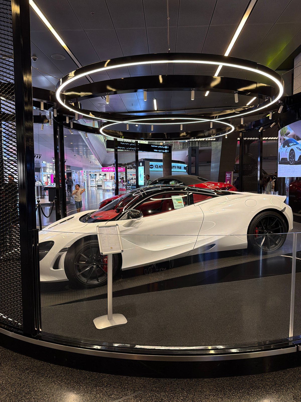 White McLaren sports car displayed in modern mall setting
