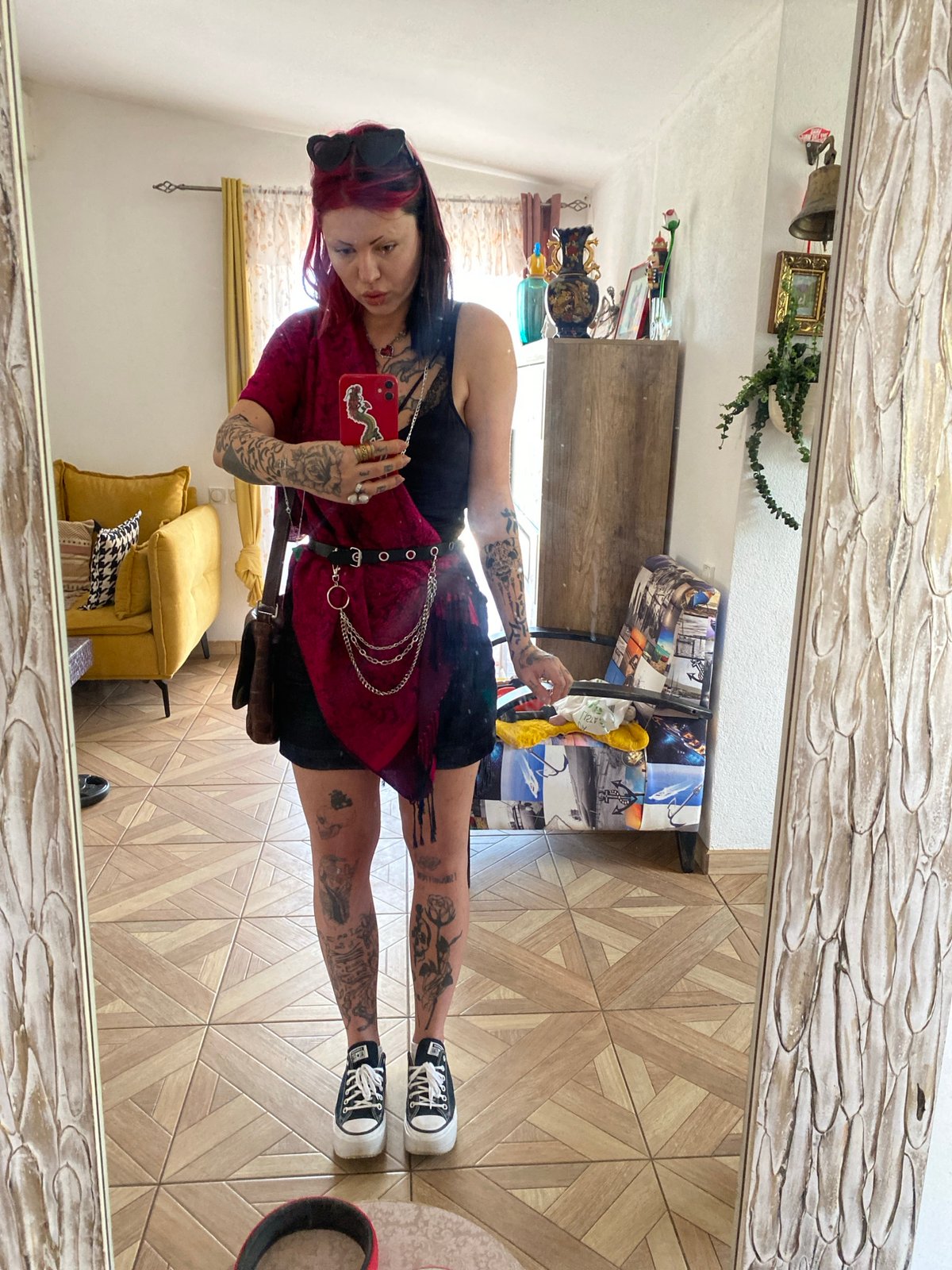 Woman takes indoor selfies with red smartphone, mirror reflections captured