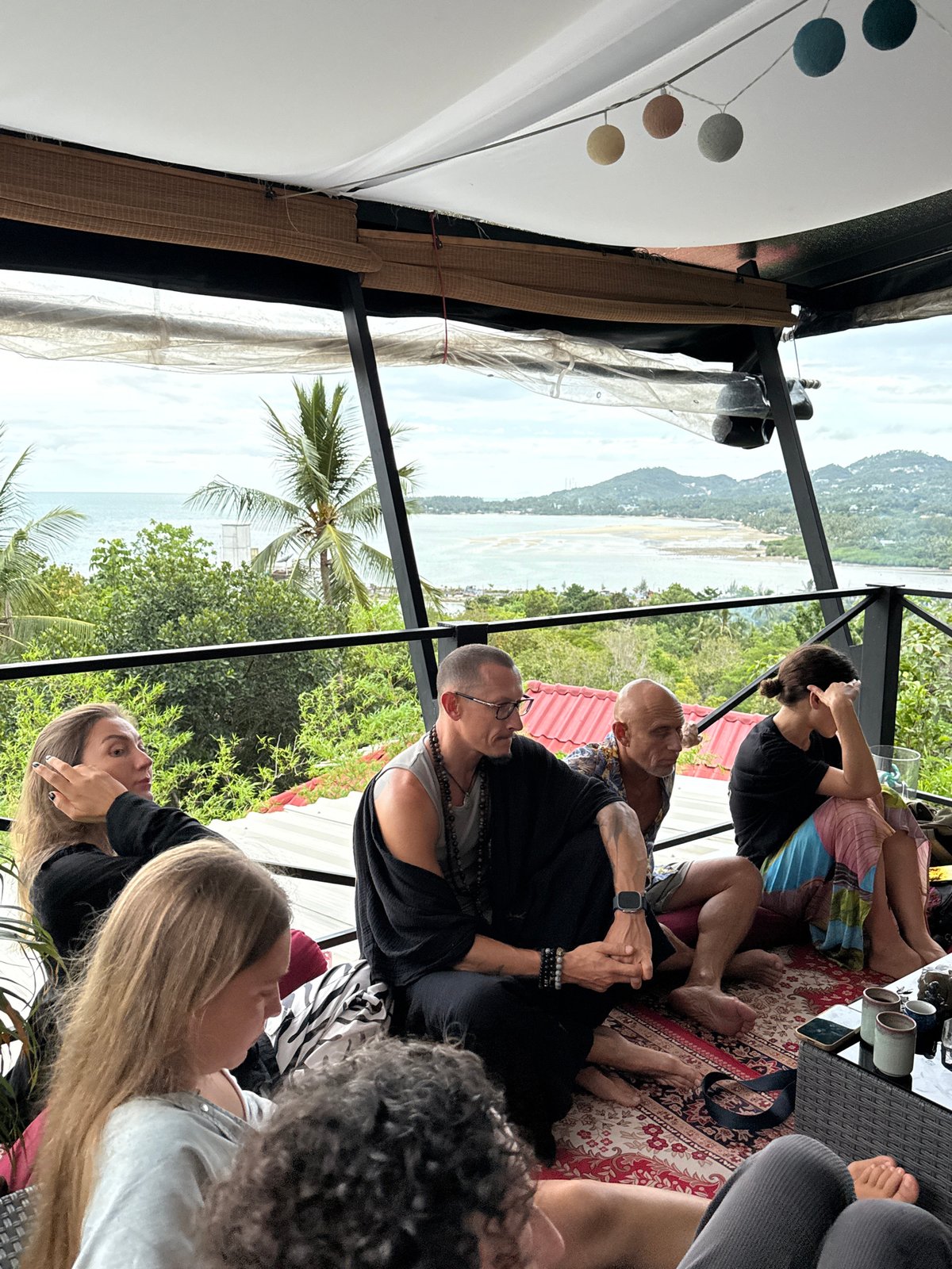 Group gathers on Ko Phangan patio overlooking coast