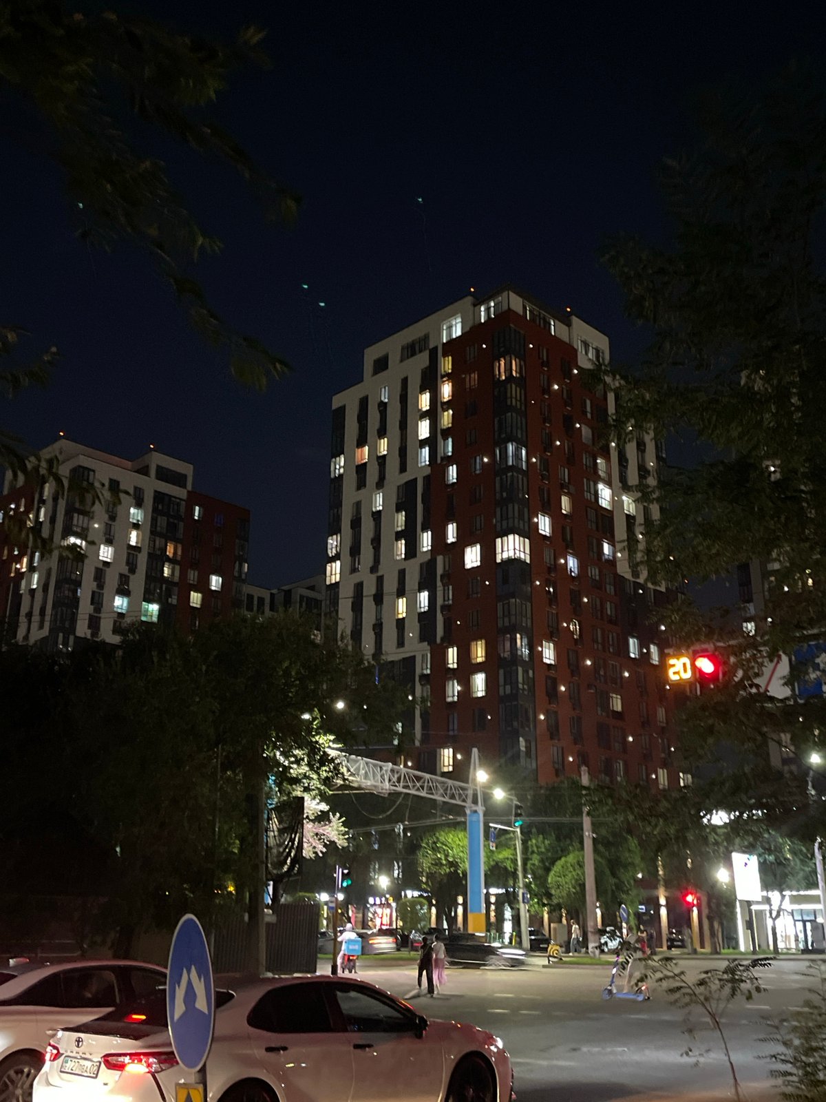 Nighttime street scene with parked bus near Almaty apartment blocks
