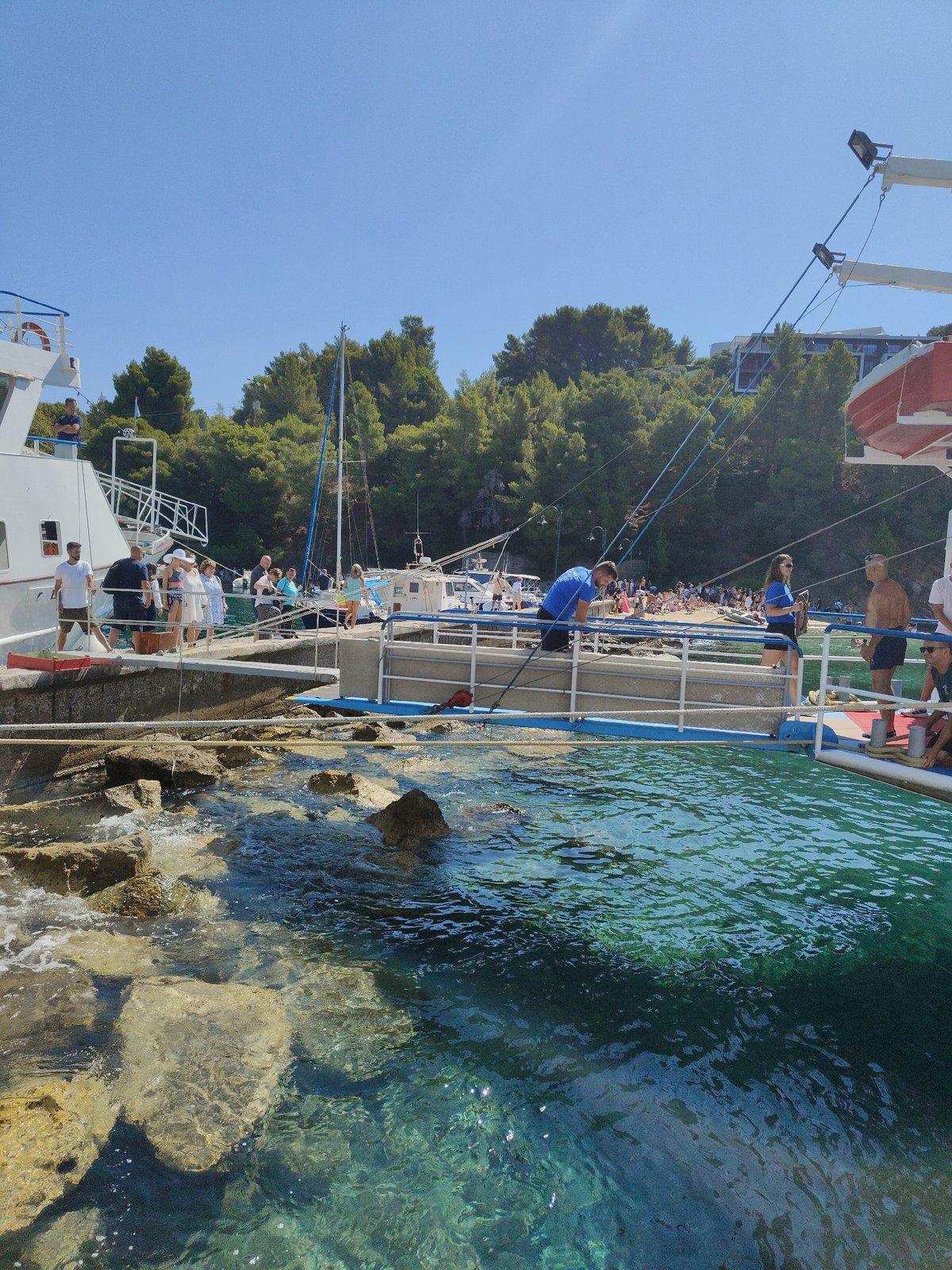 Passengers step off a white ferry onto a Greek stone pier