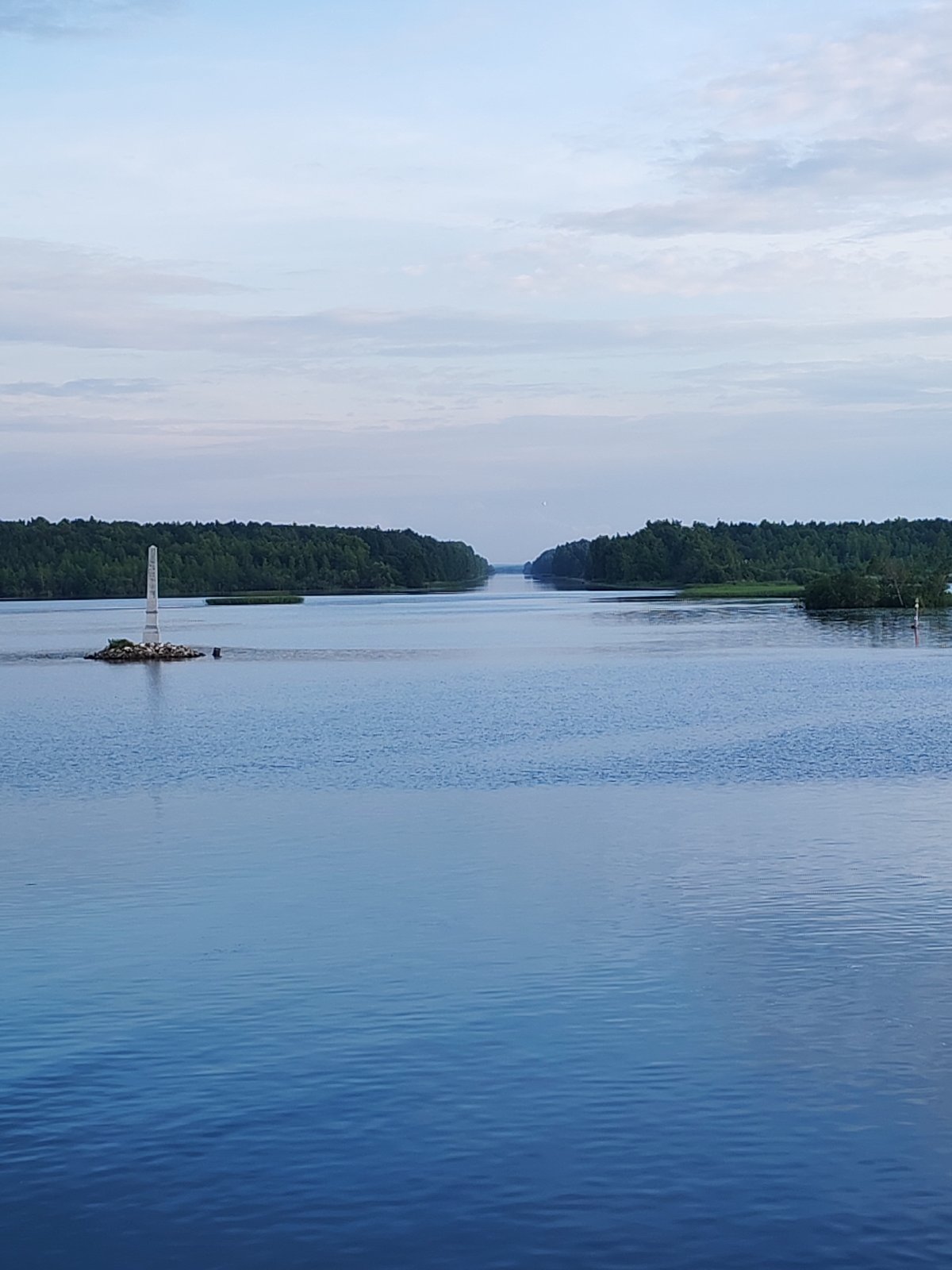 Calm Russian waterway under a partly cloudy summer sky