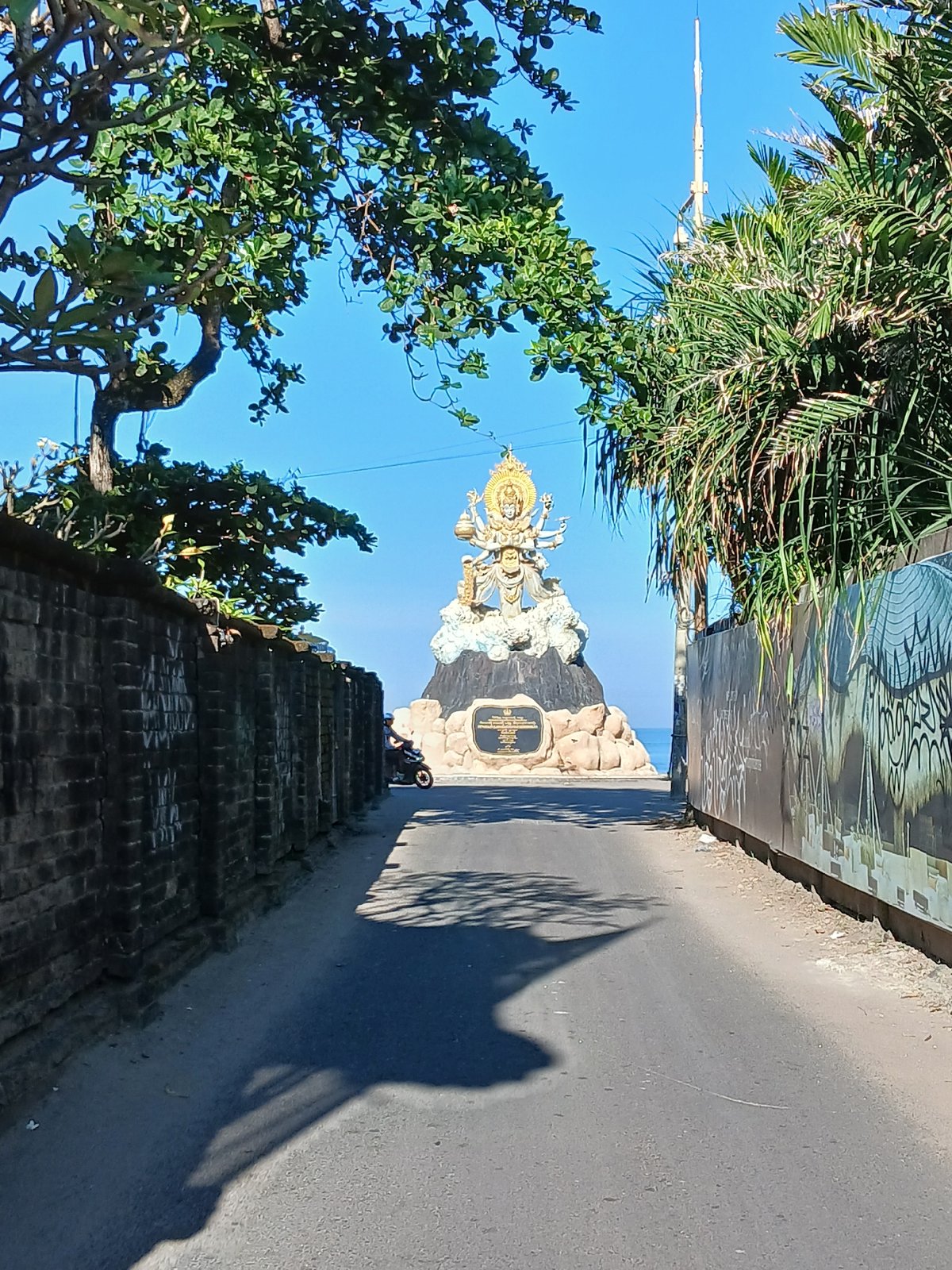 Morning beach life and a coastal deity statue in Bali