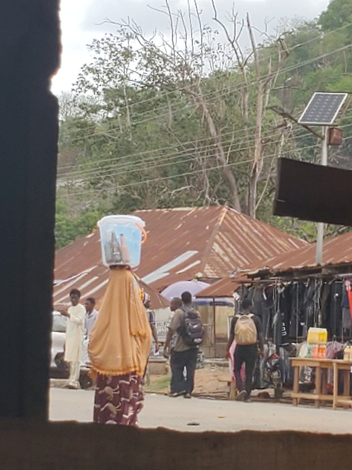 Person carries container on head in urban setting