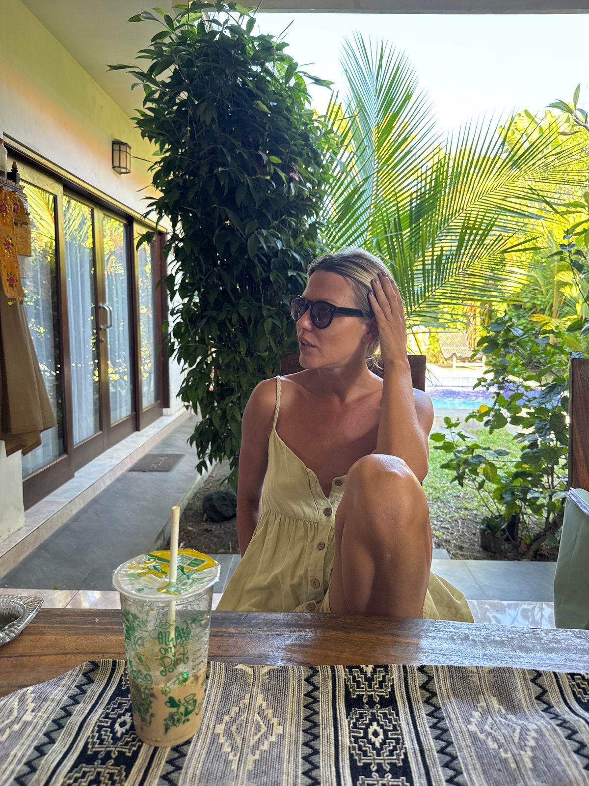 Woman enjoys morning smoke and drink on Kuta veranda