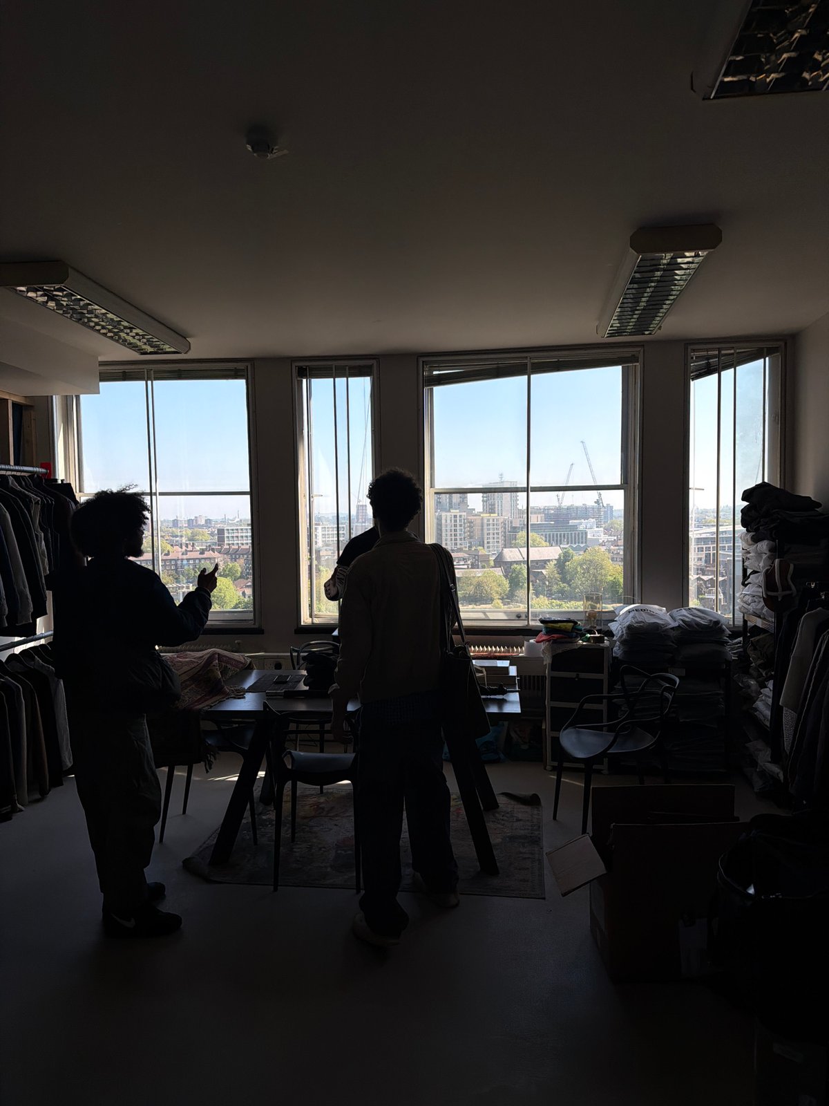Two people silhouetted against London cityscape windows in daylit room