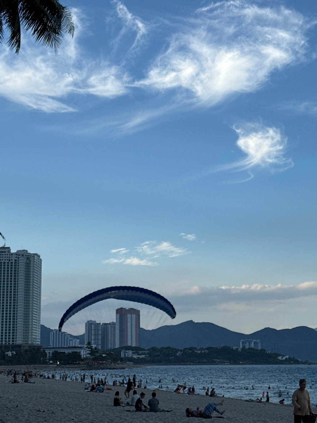 Nha Trang beach buzzing with parasailing, swimmers, and street traffic
