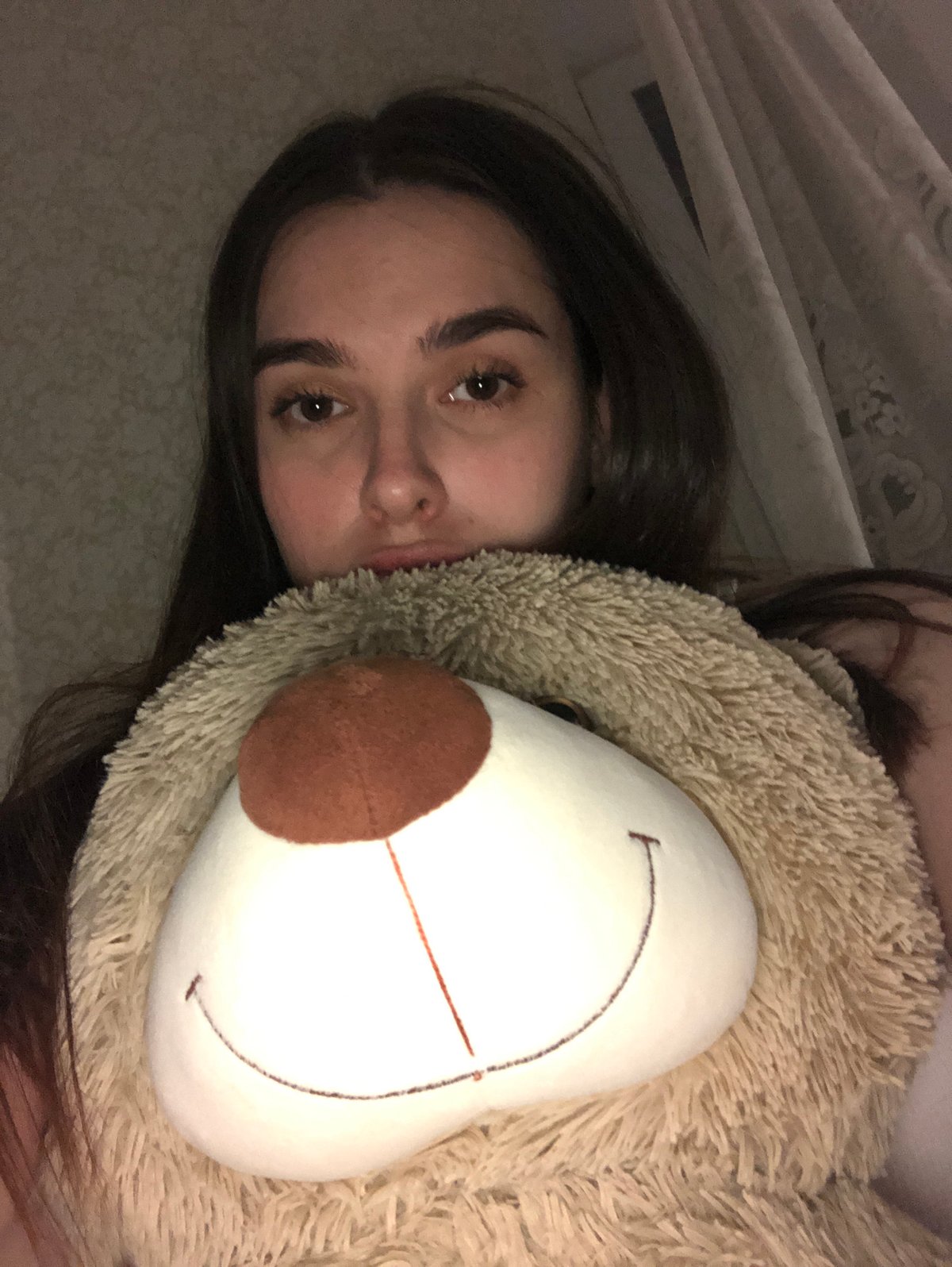Woman rests with teddy bear in Noviy bedroom
