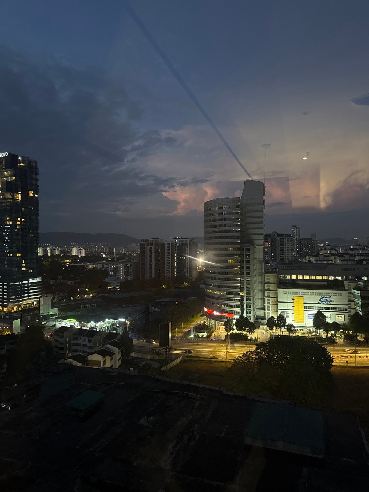 KL skyline at night, storm on the horizon, highway below