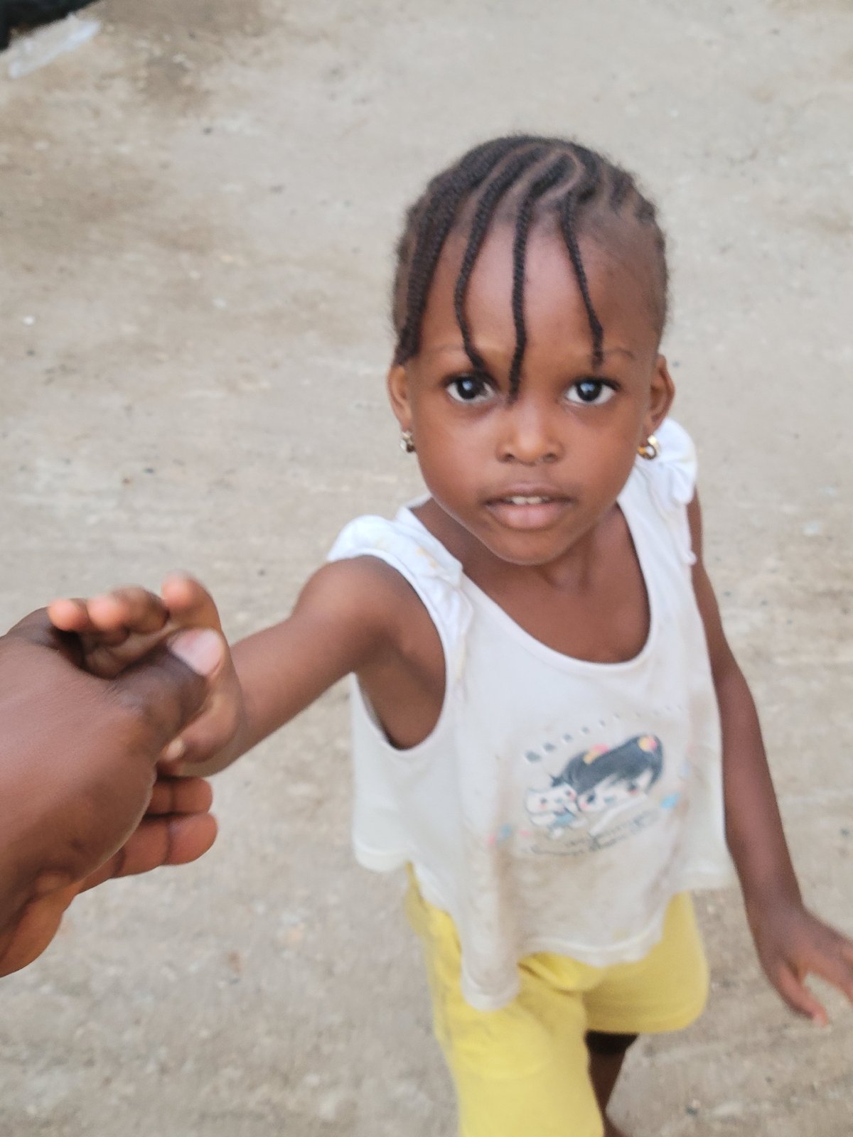 Child photographed holding adult's hand in Madalla, Nigeria
