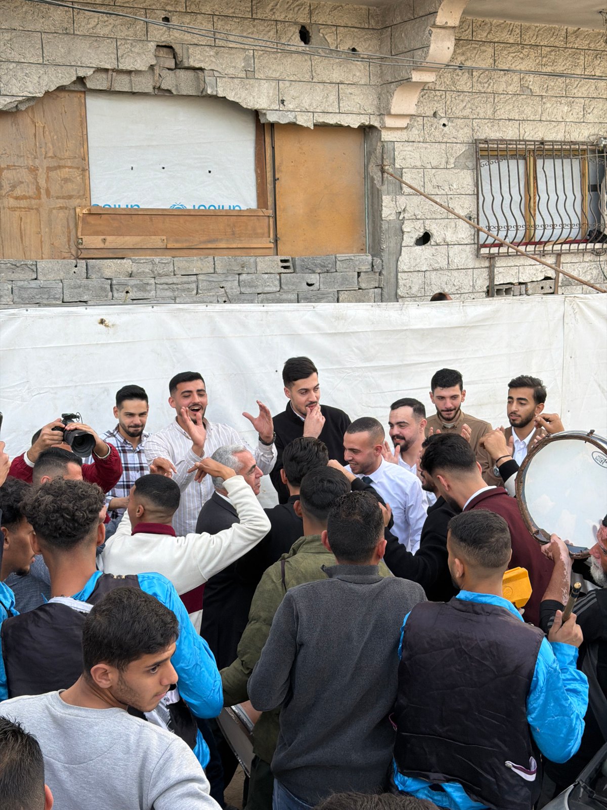 Street celebration with dancing, drumming near damaged Gaza building