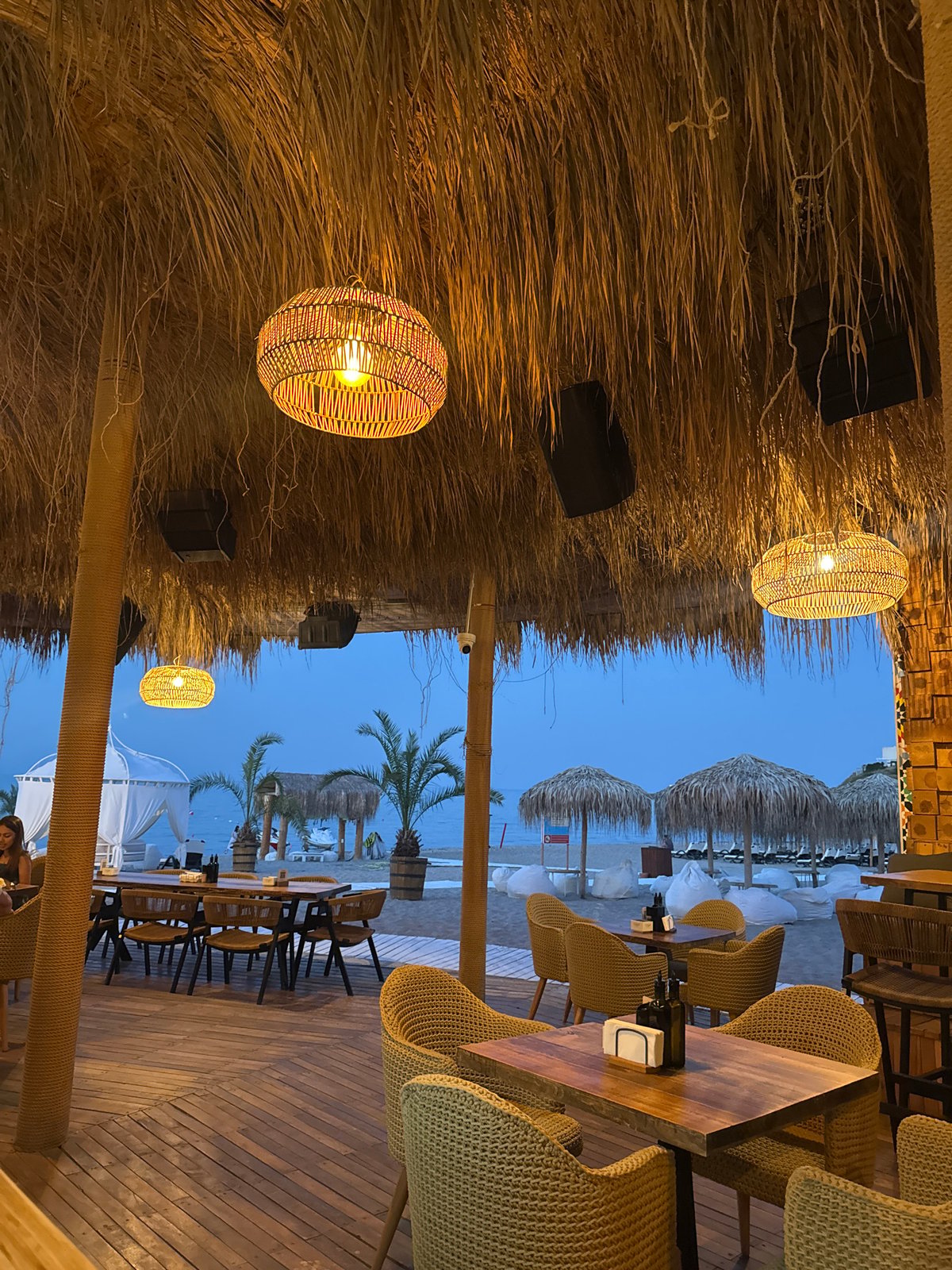 Drinks and food at a thatched beachside restaurant at dusk