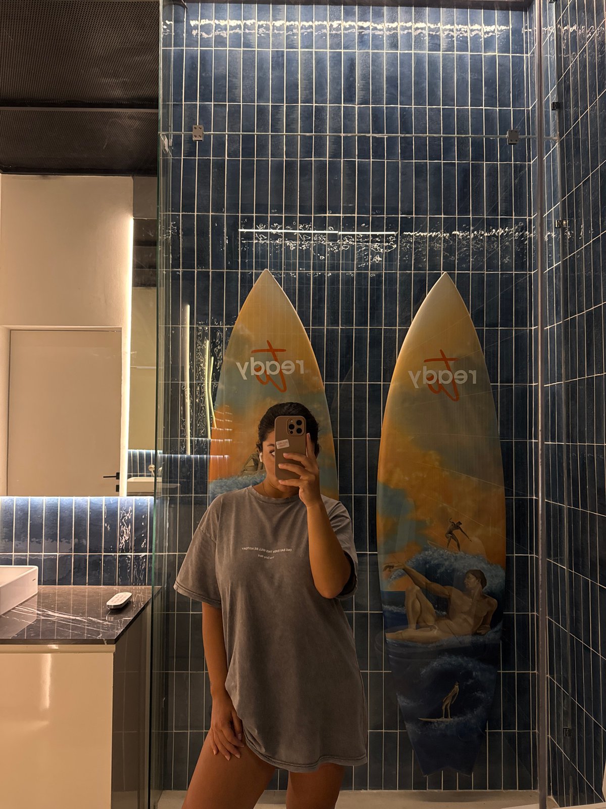 Woman takes bathroom selfie with surfboard decor in Kuta Selatan