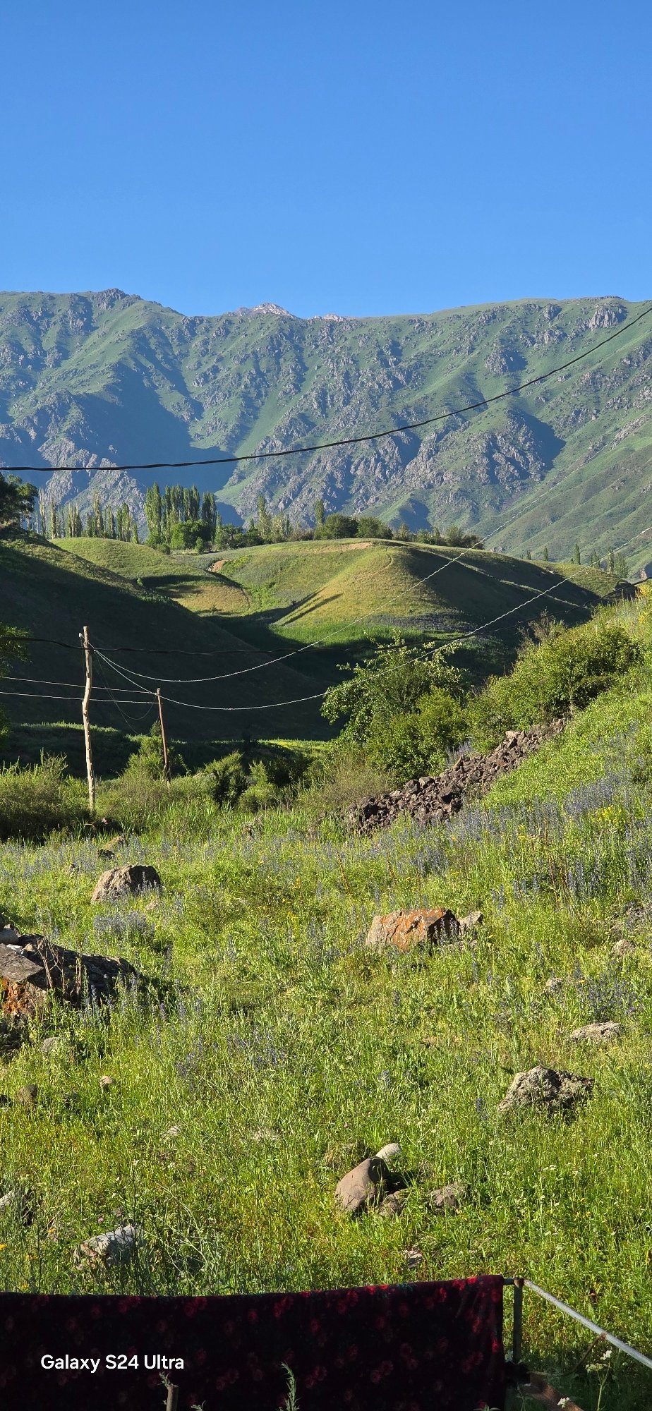 Sunny mountain slopes in Kyrgyzstan, moon visible in daylight