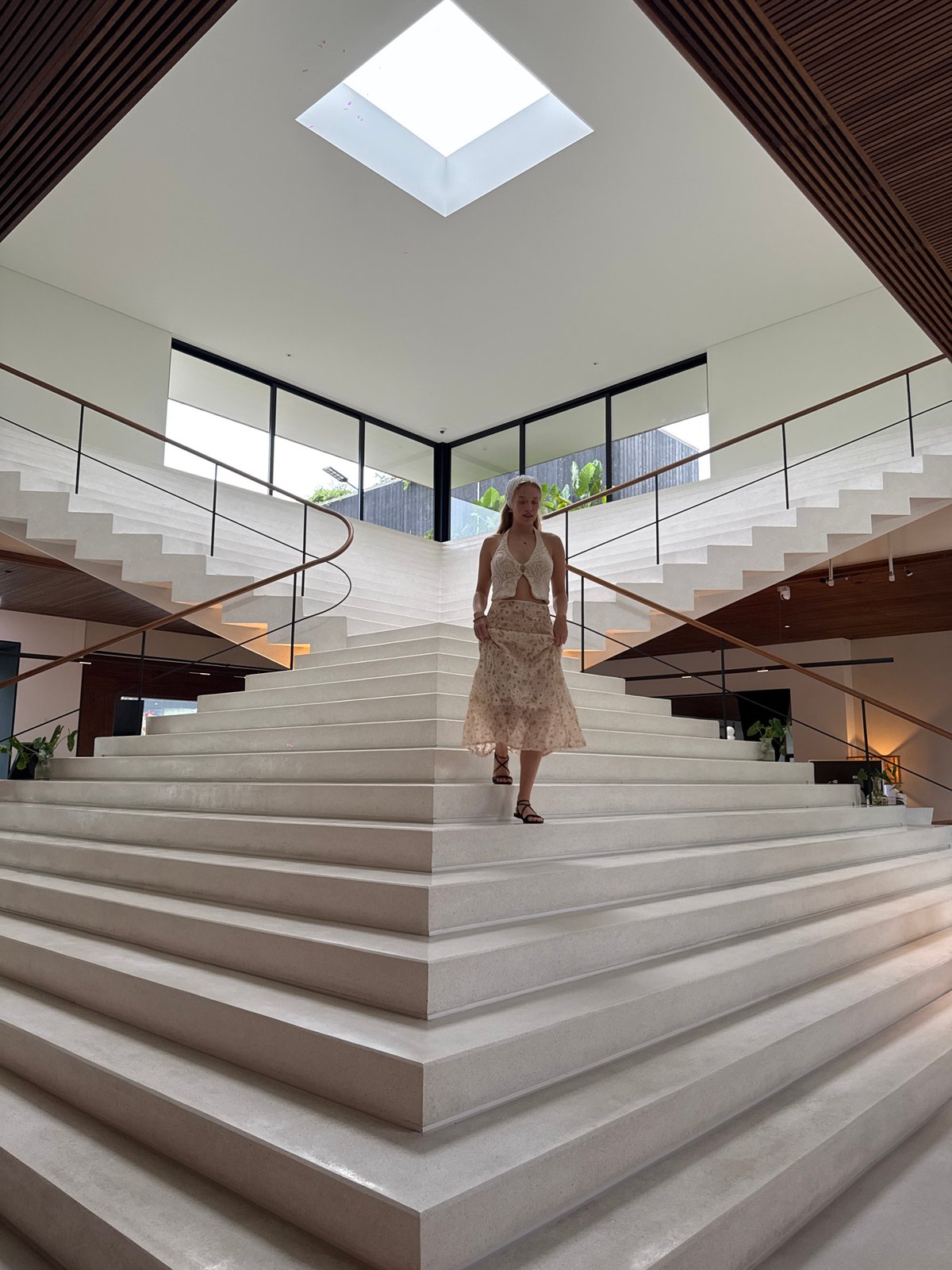 Woman walks modern split staircase in Si Sunthon building